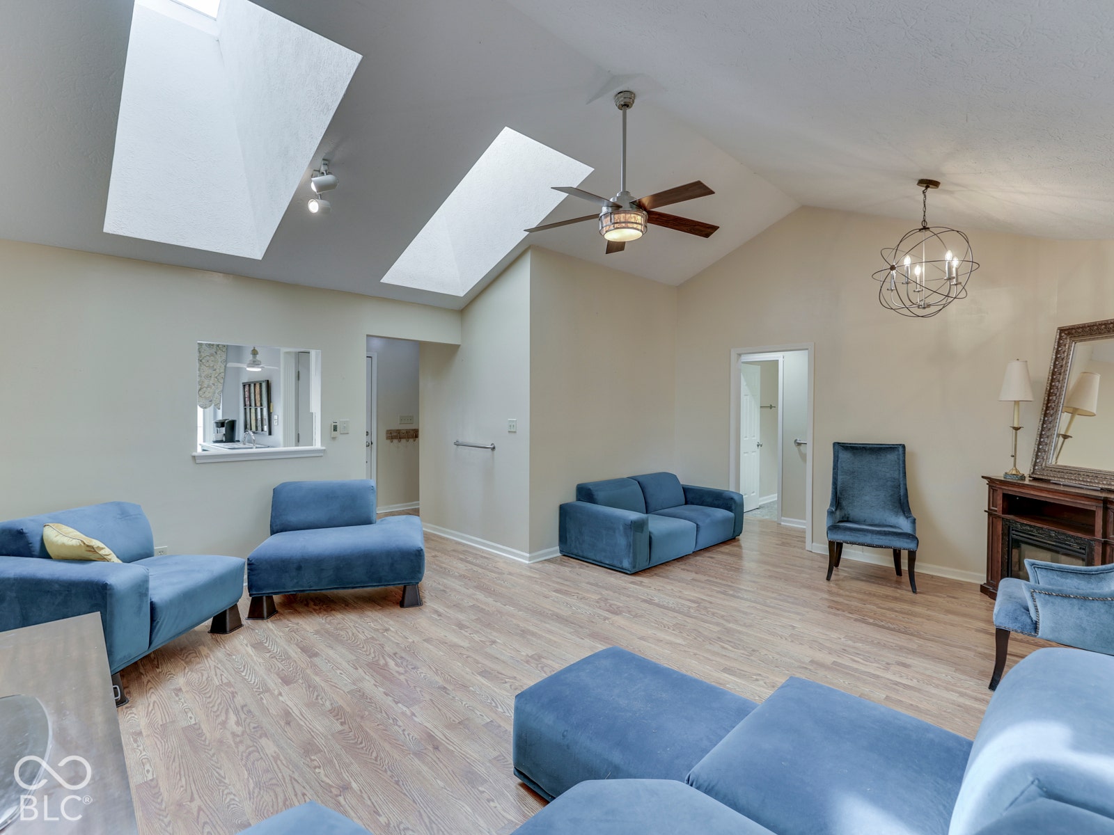 770 Ivy Lane, Greenwood, IN 46143 Vaulted ceiling featuring dual skylights, wood-finish flooring, a multi-blade ceiling fan, and a spherical metal chandelier