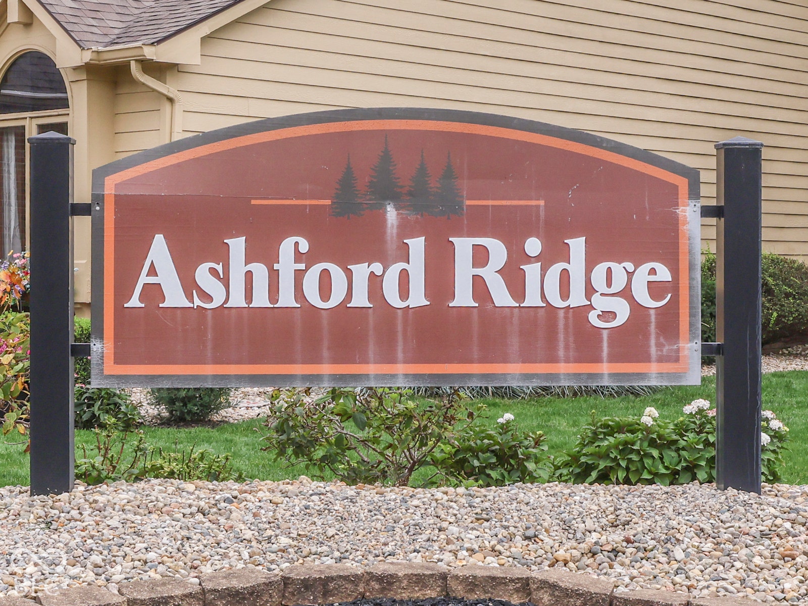 770 Ivy Lane, Greenwood, IN 46143 Freestanding Ashford Ridge monument signage featuring a brown panel, metal frame, and stone-bordered landscaping