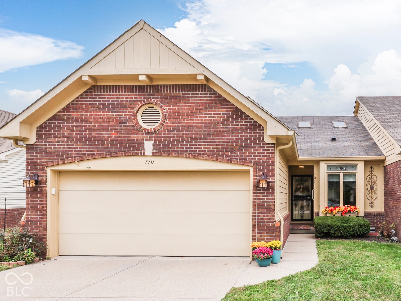 770 Ivy Lane, Greenwood, IN 46143 Brick exterior featuring a gabled roofline, arched garage entry, circular louvered vent, and skylights