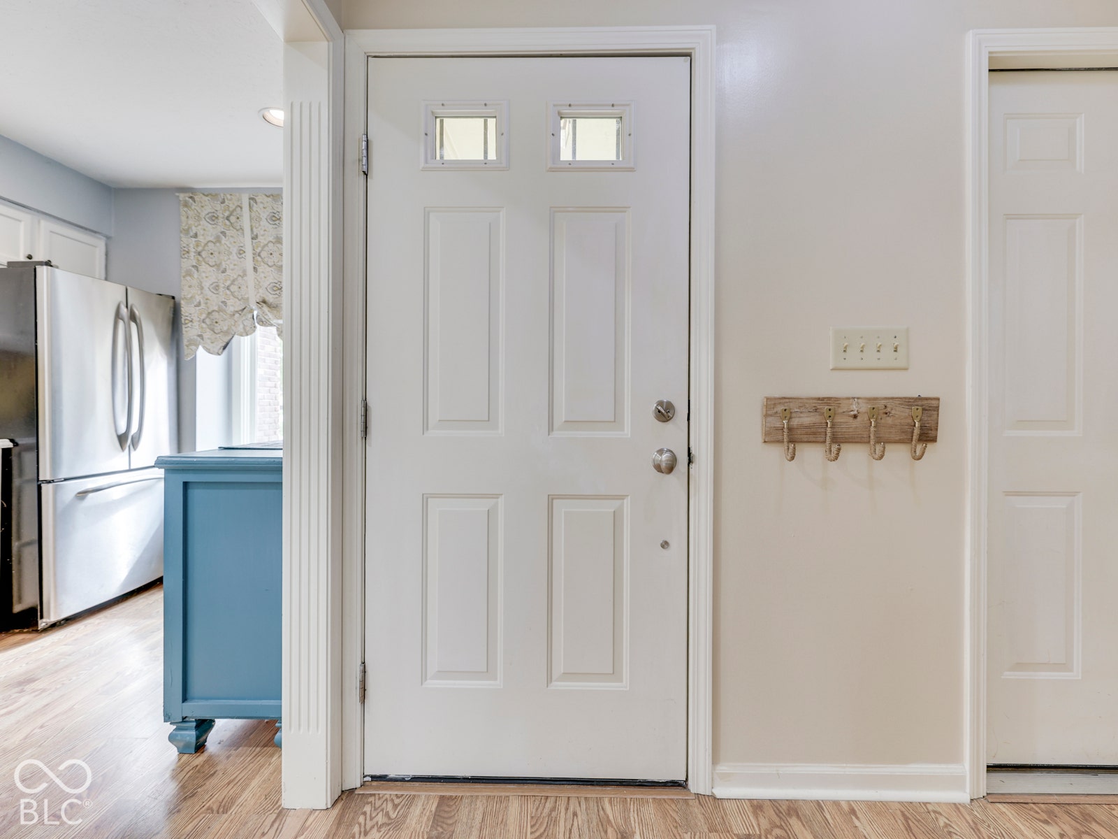 770 Ivy Lane, Greenwood, IN 46143 White four-panel entry door featuring two rectangular glass panes, vertical fluted trim casing, and light-toned wood-finish flooring