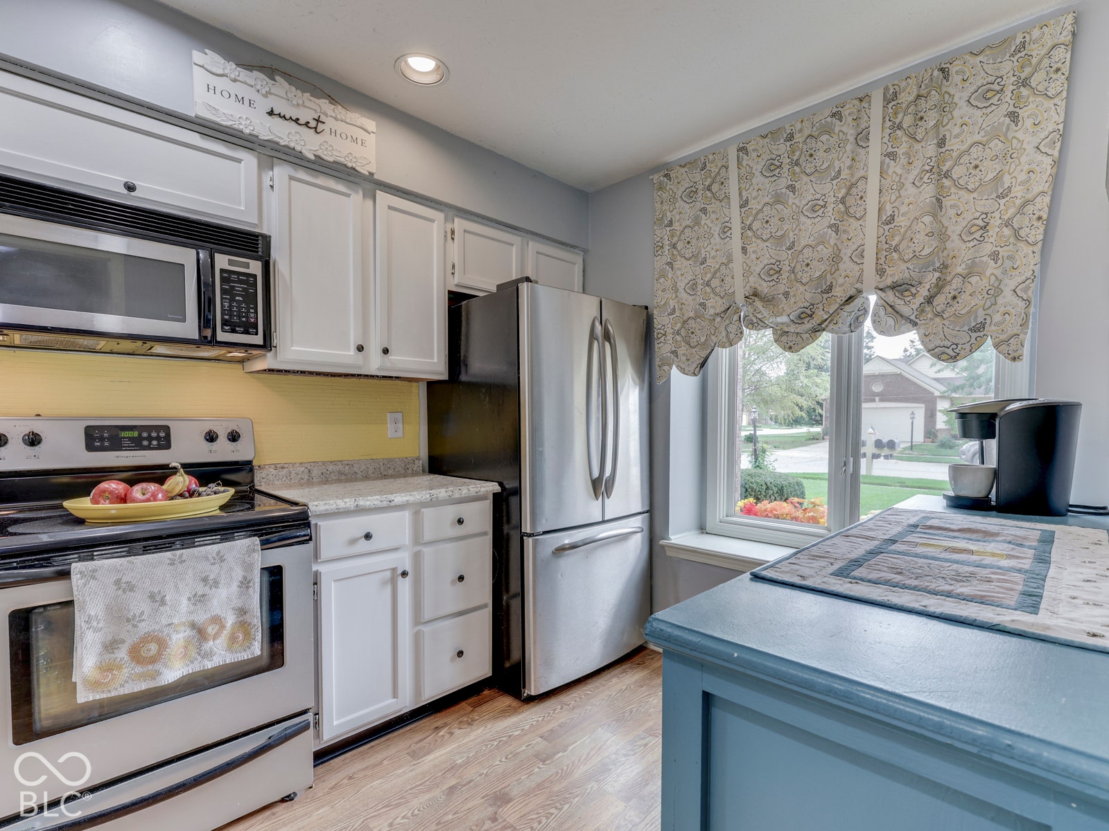 770 Ivy Lane, Greenwood, IN 46143 Kitchen featuring white cabinetry, stone-finish countertops, stainless steel appliances, wood-finish flooring, and a large window