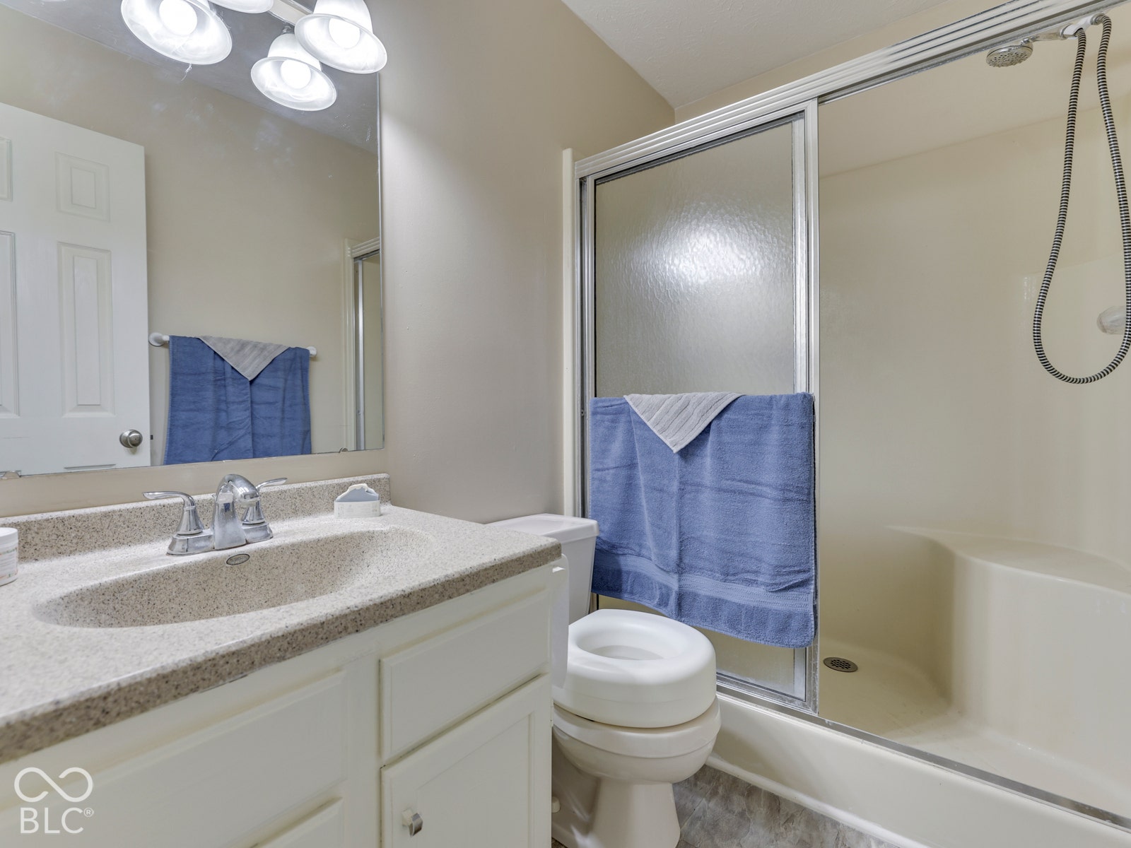 770 Ivy Lane, Greenwood, IN 46143 Bathroom featuring a vanity with an integrated countertop and sink, framed mirror with integrated vanity lighting, and a shower enclosure with sliding glass doors and a built-in seat