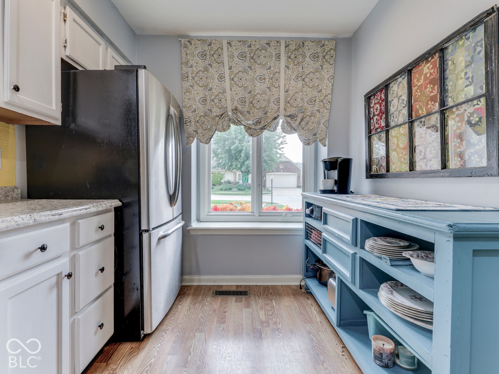 770 Ivy Lane, Greenwood, IN 46143 Kitchen featuring white cabinetry, wood-finish flooring, stainless steel refrigerator, and a window centered above the floor space