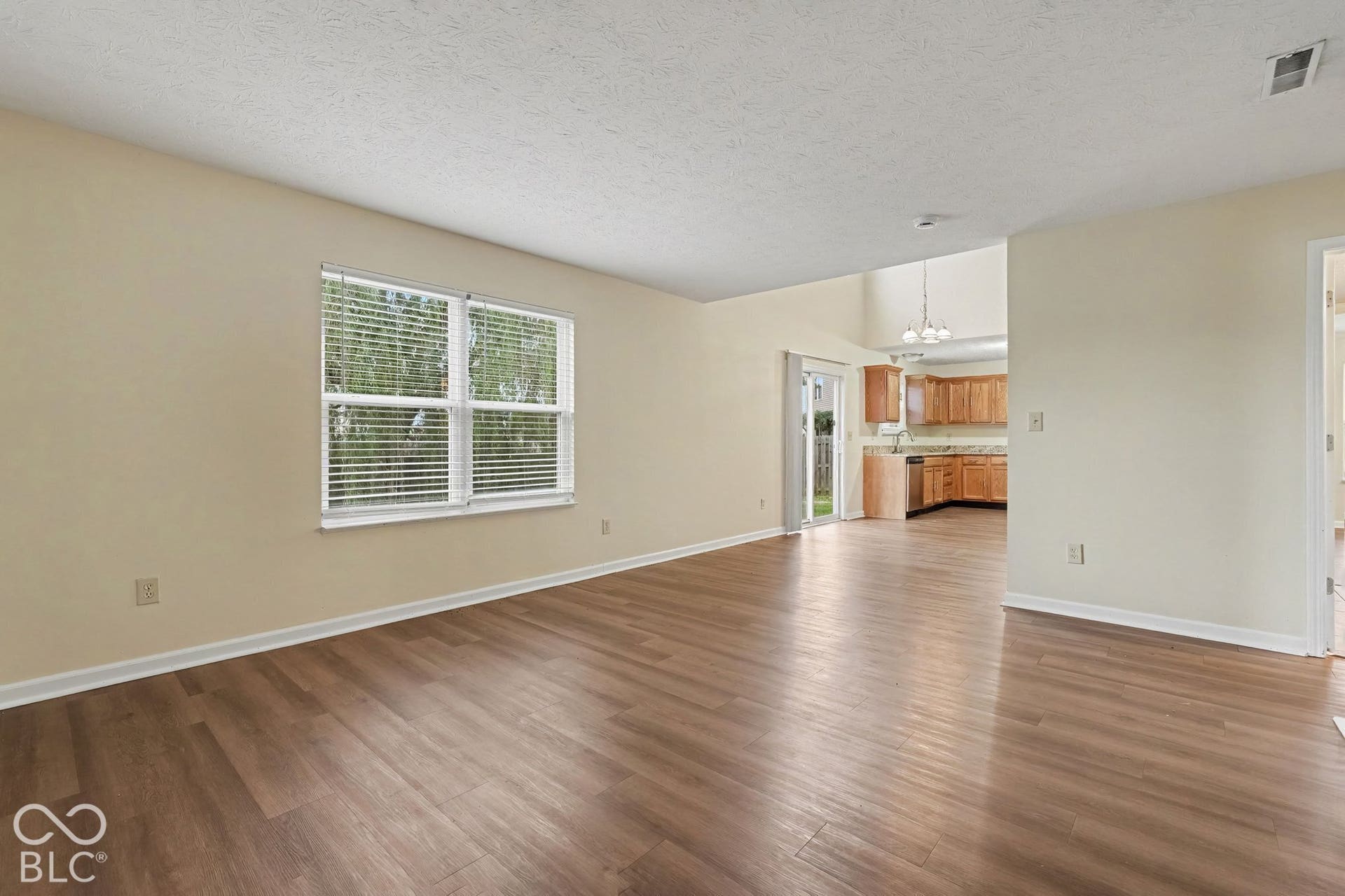 Living area featuring wood-finish flooring, neutral wall paint, and multi-pane window with blinds