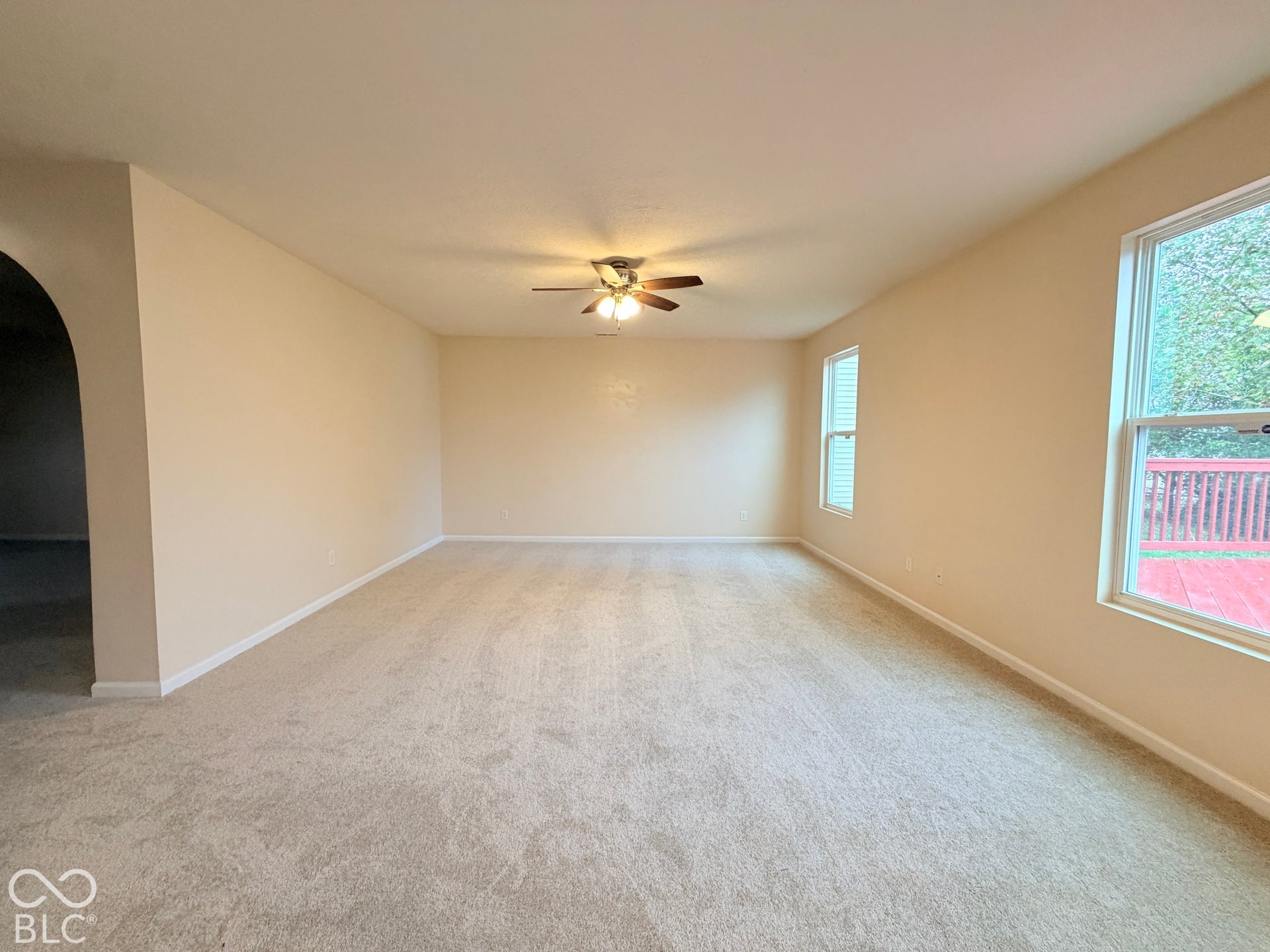 Neutral wall-to-wall carpeting, ceiling fan with light fixture, and large dual-pane windows