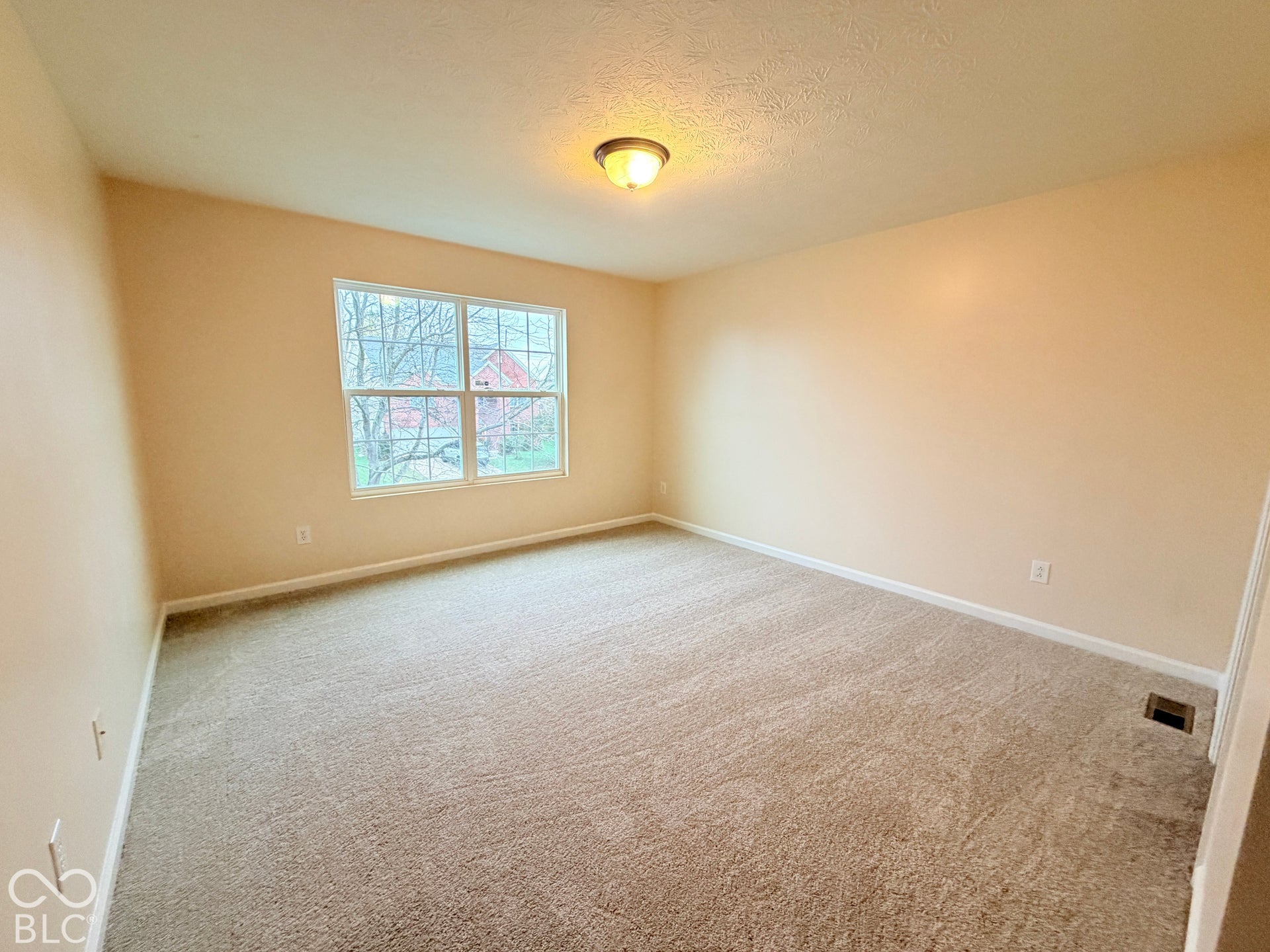 Interior room featuring neutral wall paint, wall-to-wall carpeting, and a double-pane window with a muntin grid
