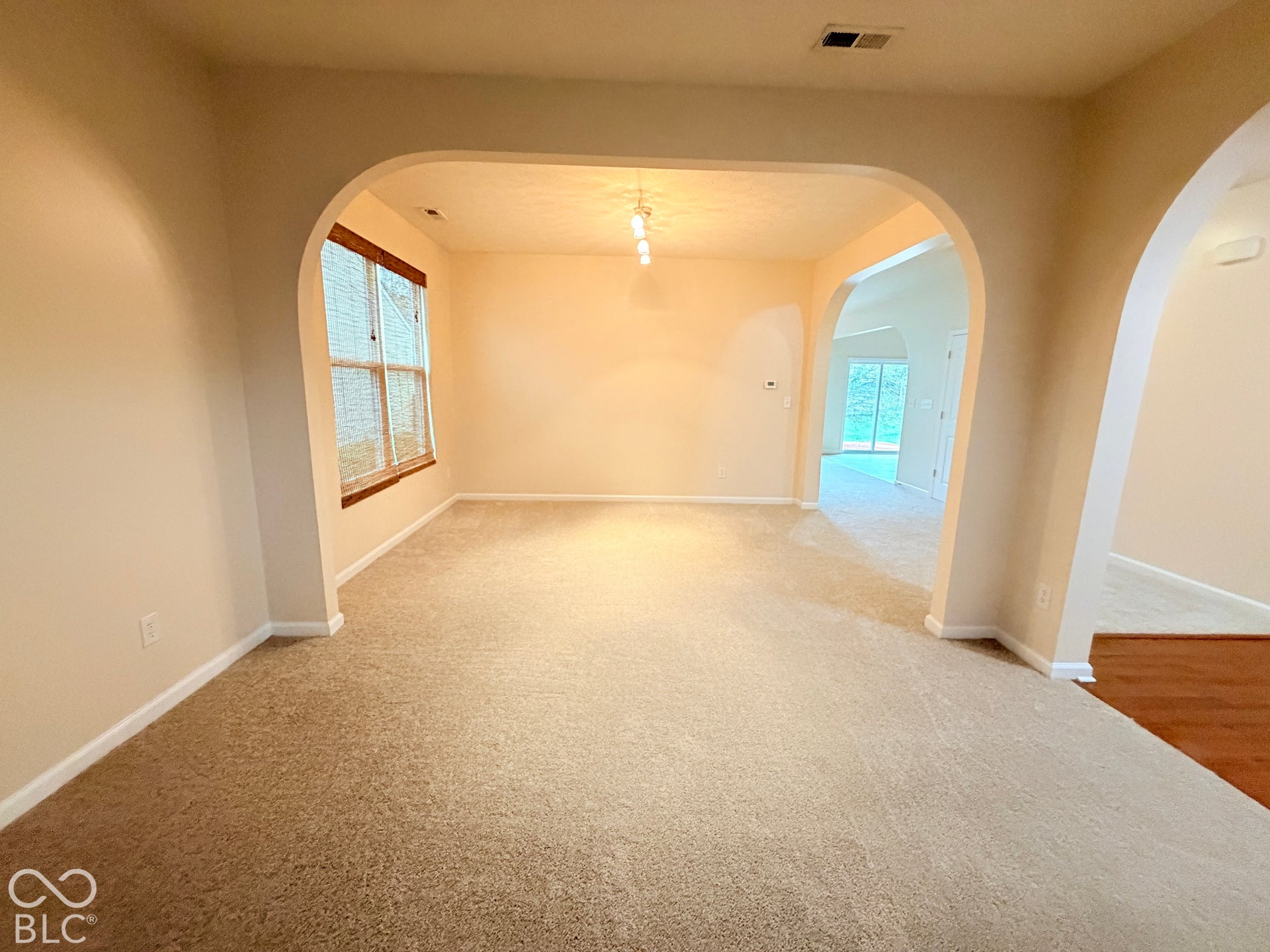 Architectural archways, multi-pane windows with trim, neutral wall coloring, and wall-mounted overhead lighting