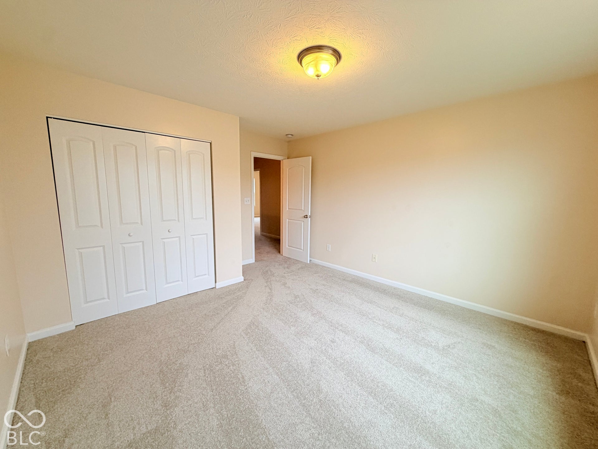 Neutral-toned carpeted flooring, multi-panel bi-fold closet doors, and flush-mount lighting fixture
