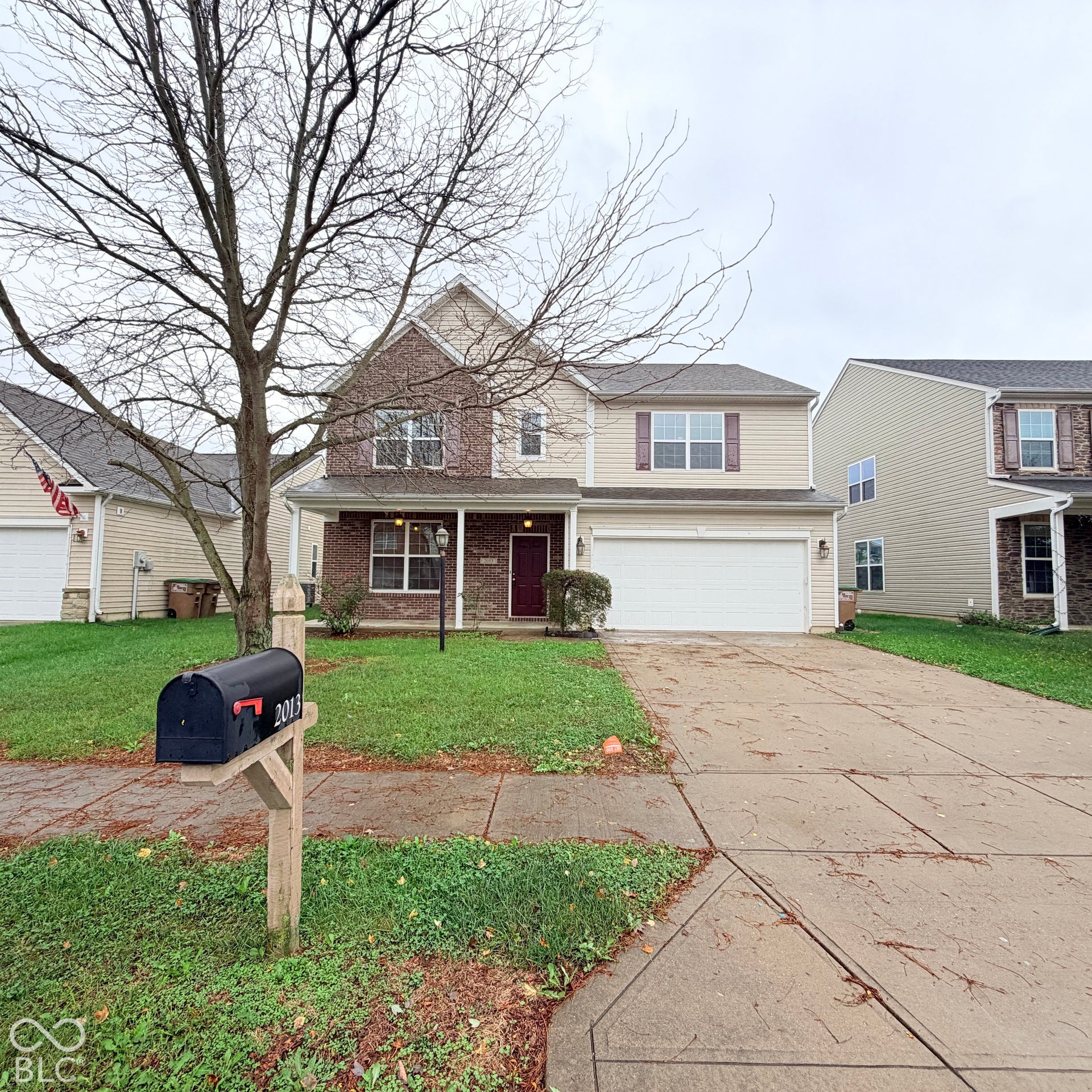 Two-story residence with a brick and vinyl siding exterior, featuring a covered front porch, an attached two-car garage, and a concrete driveway