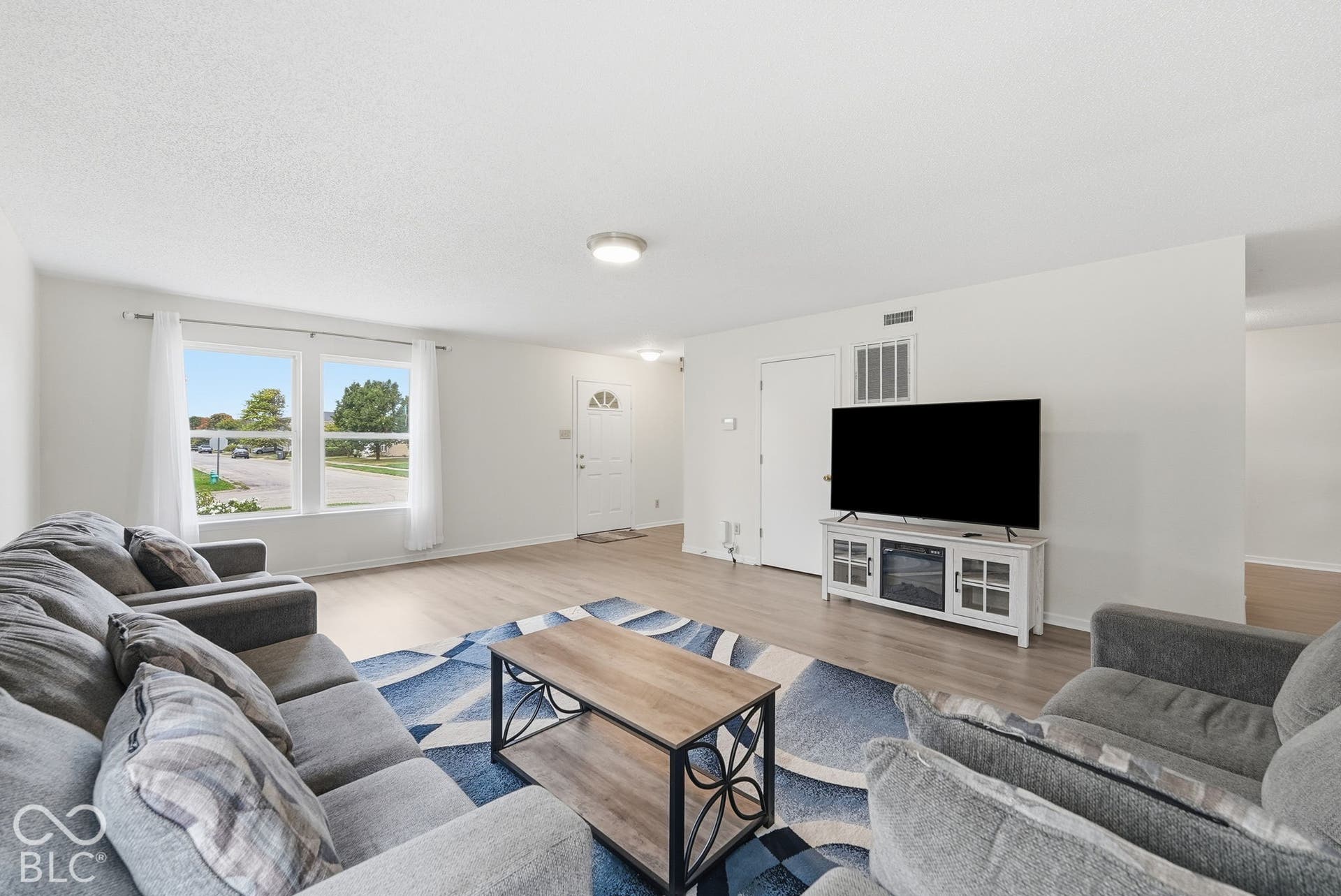 Living area featuring light-toned wood-finish flooring, neutral wall paint, and large double-pane windows