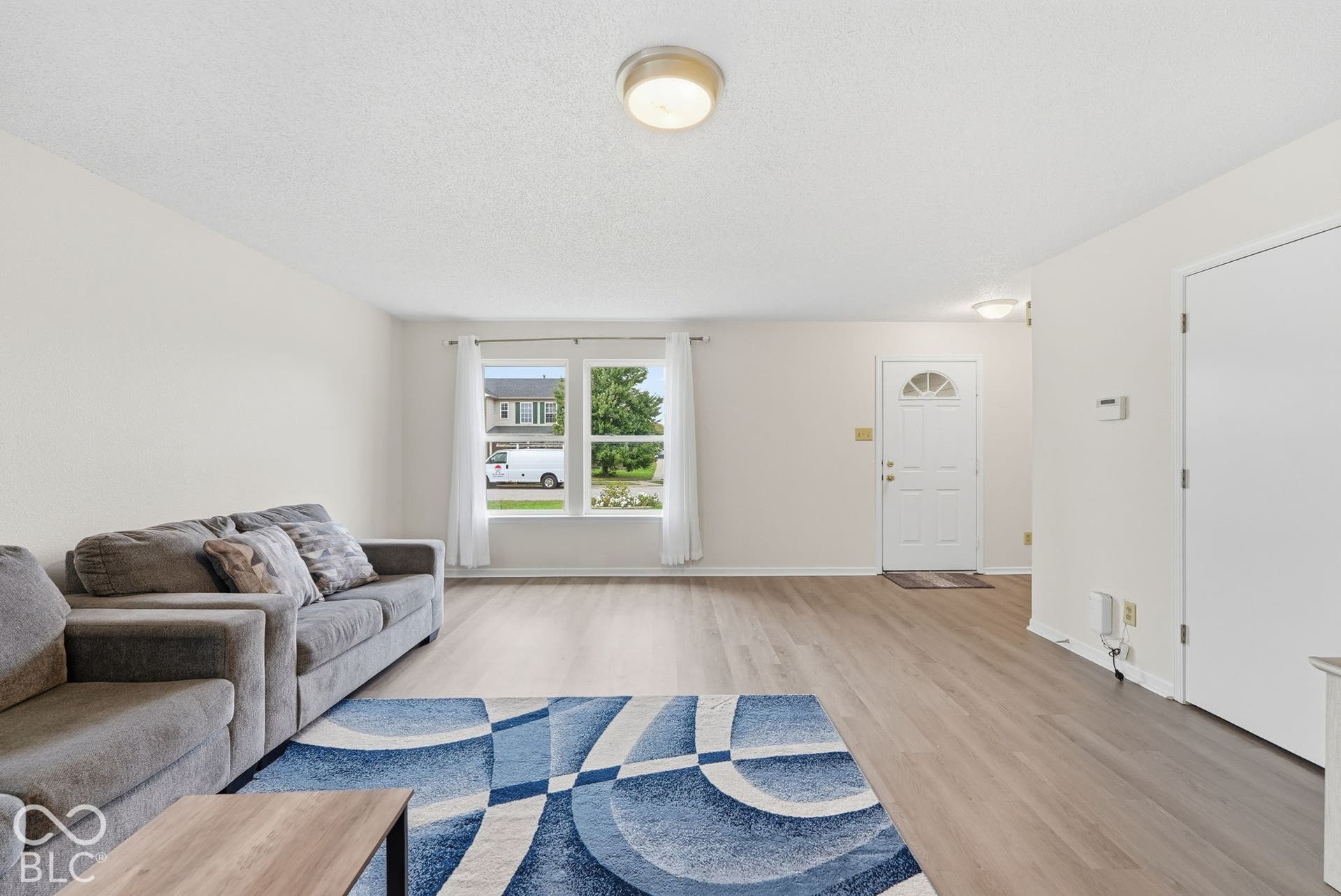 Neutral interior featuring wood-finish flooring, crisp white walls, dual-pane windows, and flush-mount ceiling lighting