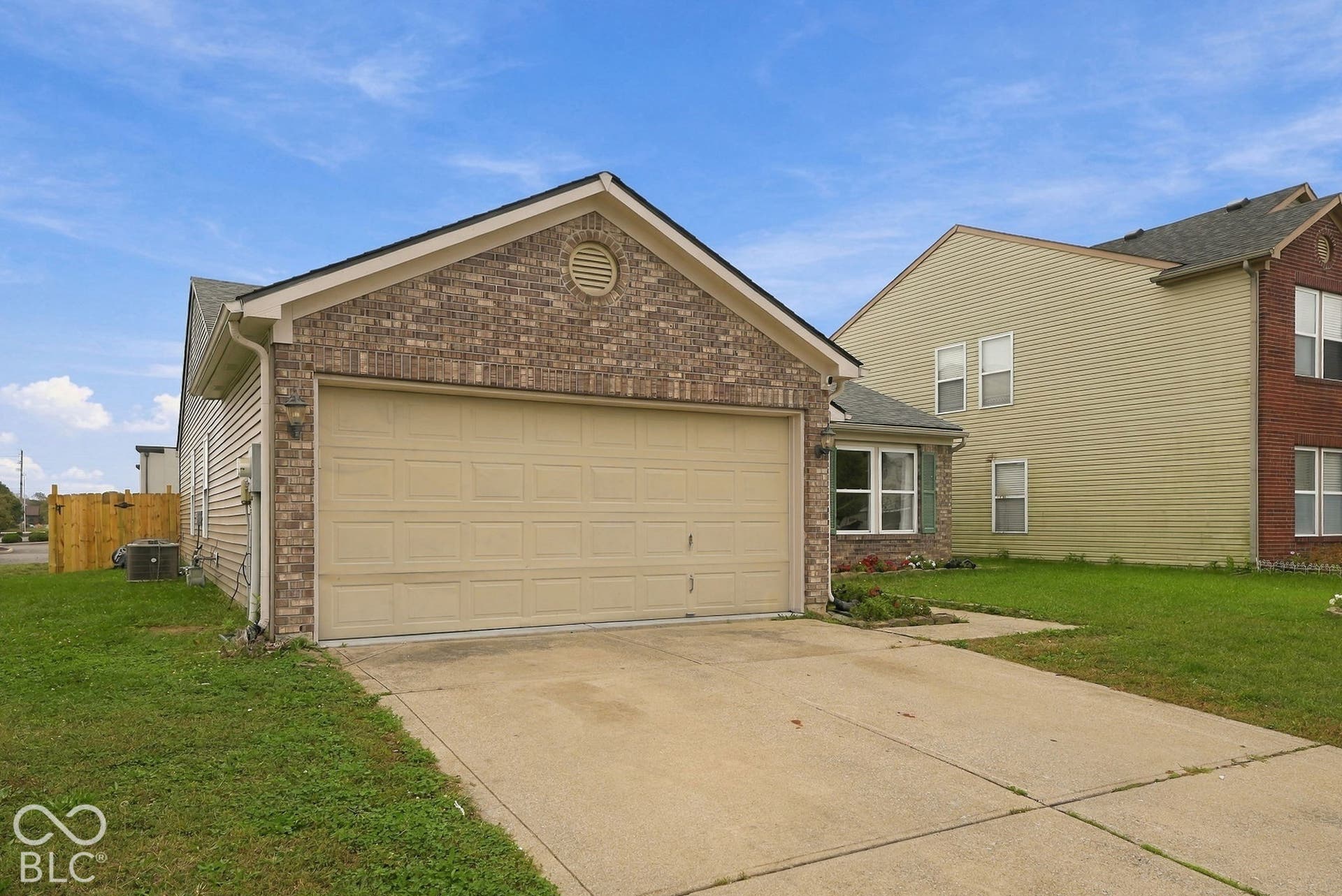 Brick veneer exterior featuring a two-car garage, gable roofline, and concrete driveway