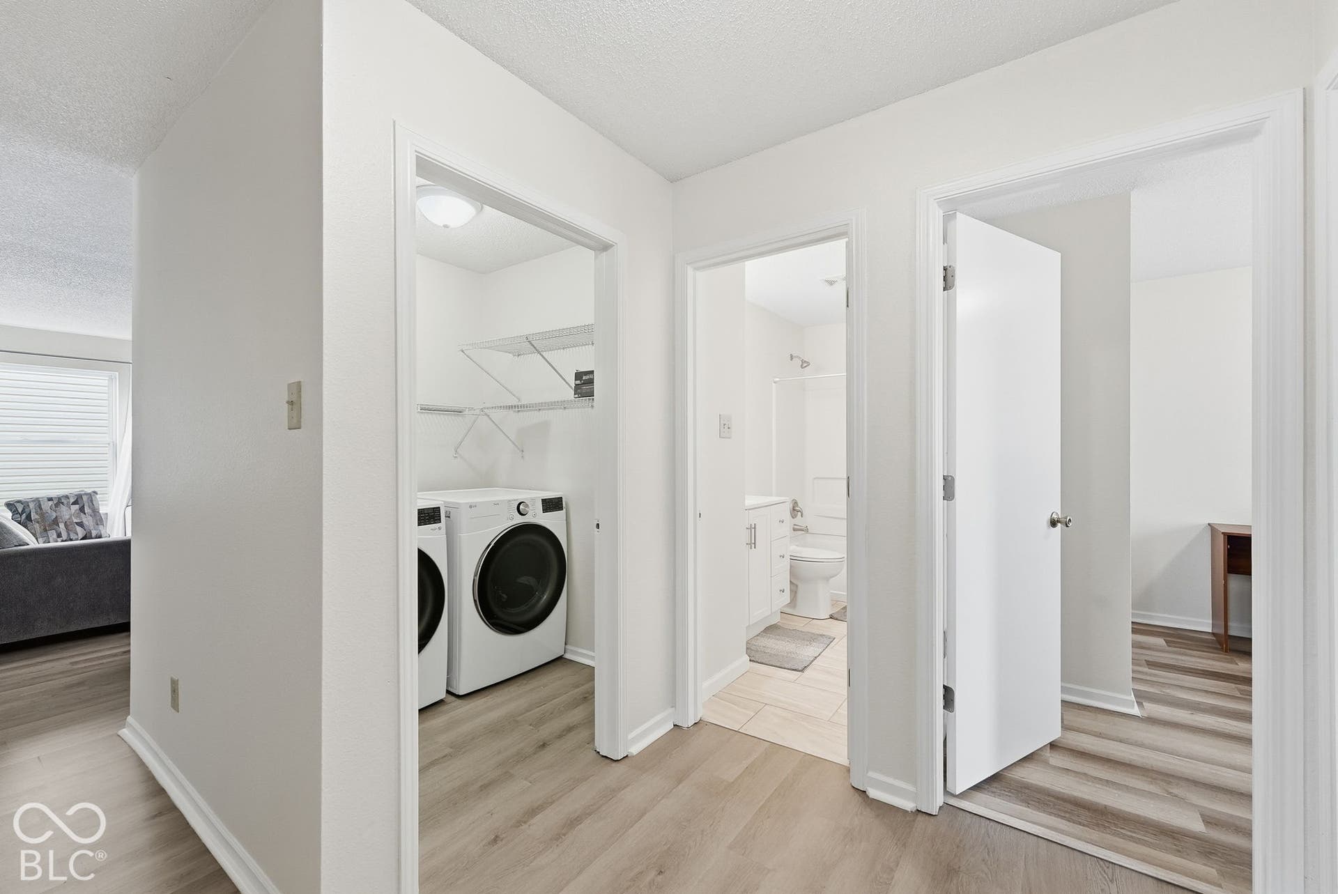 Neutral-toned wood-finish flooring, dedicated laundry nook with built-in shelving, and tile flooring in the bathroom