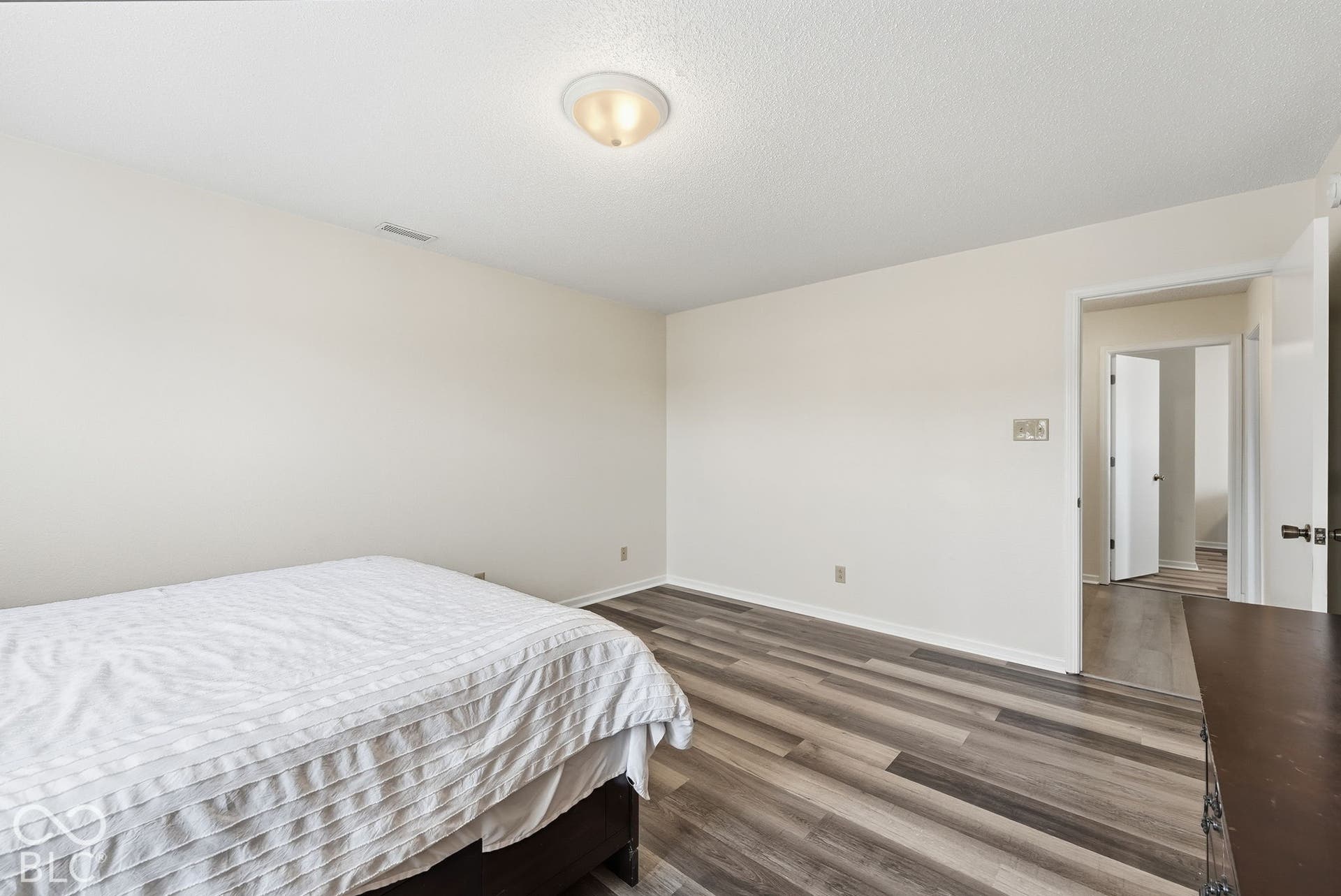 Neutral interior featuring wood-finish flooring, white walls, and a flush-mount ceiling light fixture