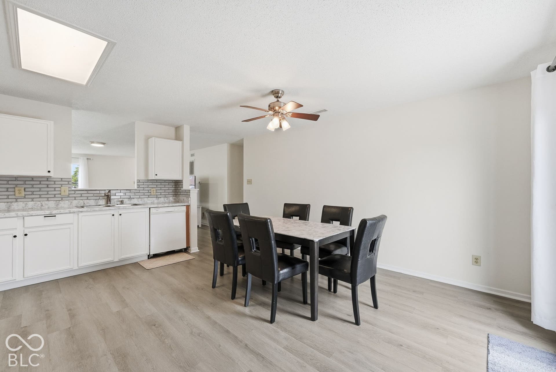 Kitchen featuring white shaker cabinetry, stone-finish countertops, grey subway tile backsplash, wood-finish flooring, and a ceiling-mounted light fixture