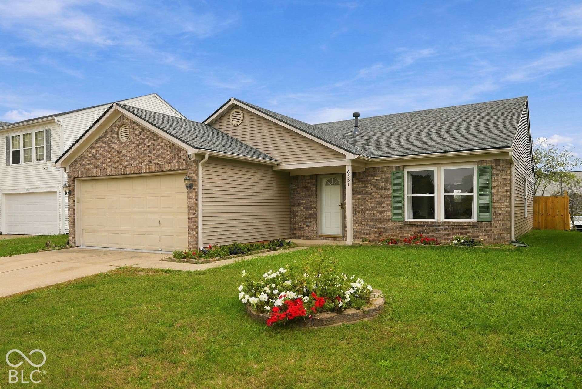 Exterior facade featuring brick masonry and horizontal siding, a gabled roofline, an attached two-car garage, and decorative window shutters