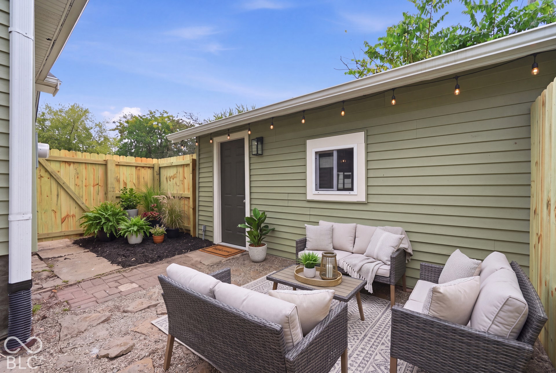 Exterior patio featuring a natural stone and paver surface, horizontal lap siding, and enclosed wood privacy fencing