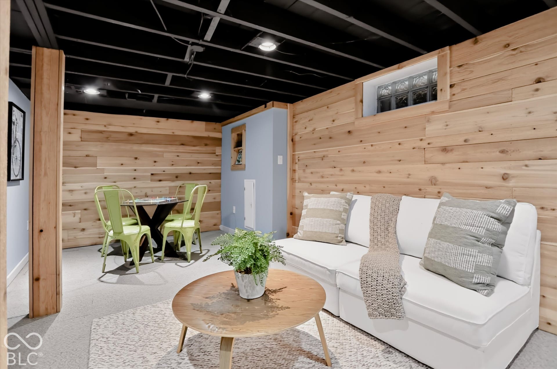 Finished interior space featuring horizontal wood-plank wall paneling, an exposed painted ceiling with recessed lighting, and a glass-block window