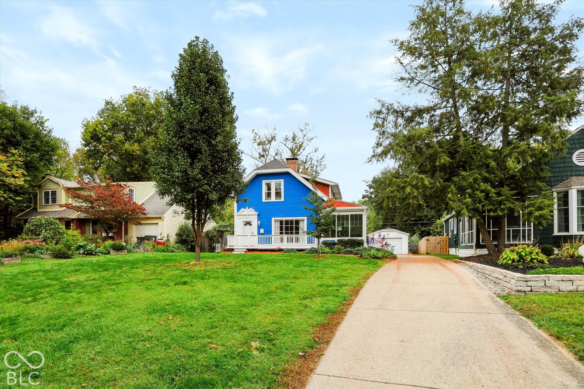 Exterior featuring blue siding, a front porch, a concrete driveway, and a detached garage