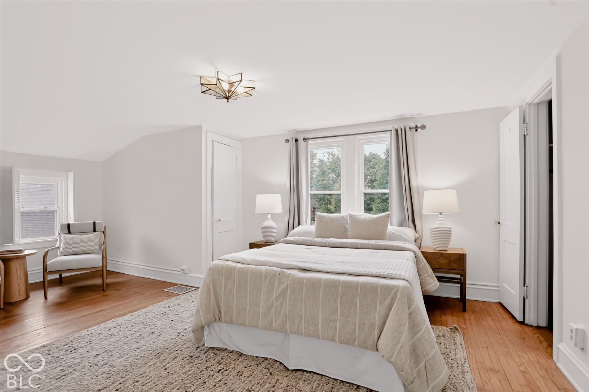Bedroom featuring wood-finish flooring, multi-pane windows, and geometric ceiling-mounted lighting