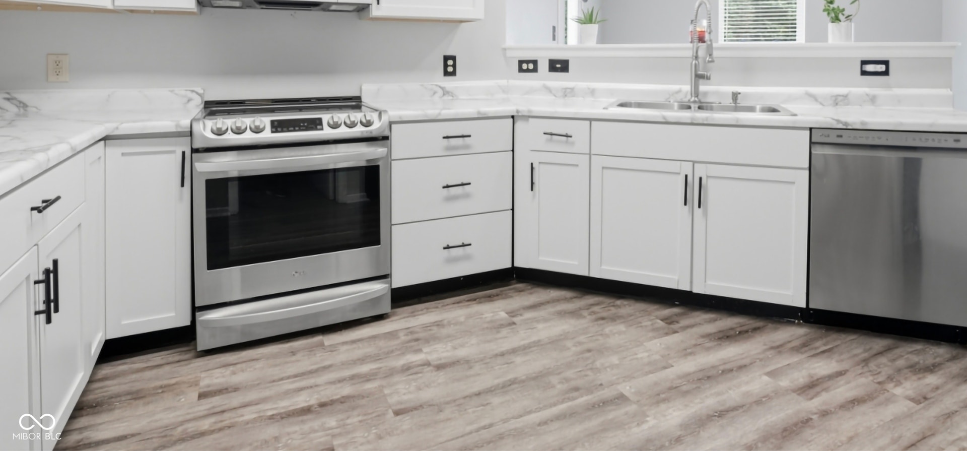 Modern kitchen featuring white cabinetry, stone-finish countertops, stainless steel appliances, and wood-finish flooring