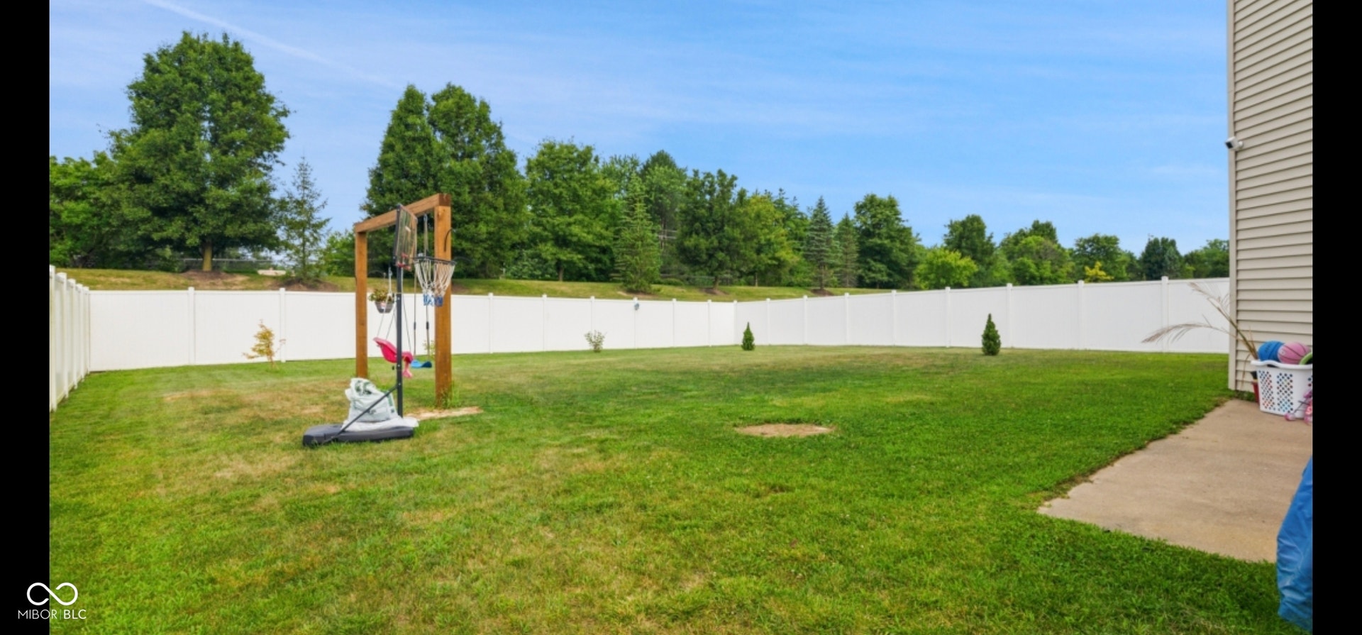 Expansive green lawn surrounded by a white privacy fence