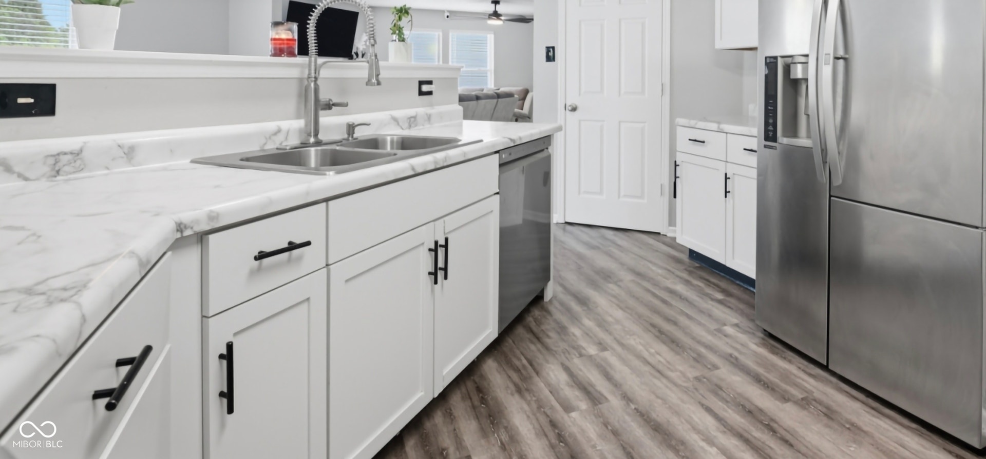 Kitchen featuring wood-finish flooring, white cabinetry with matte black hardware, and a double basin stainless steel sink with a gooseneck faucet