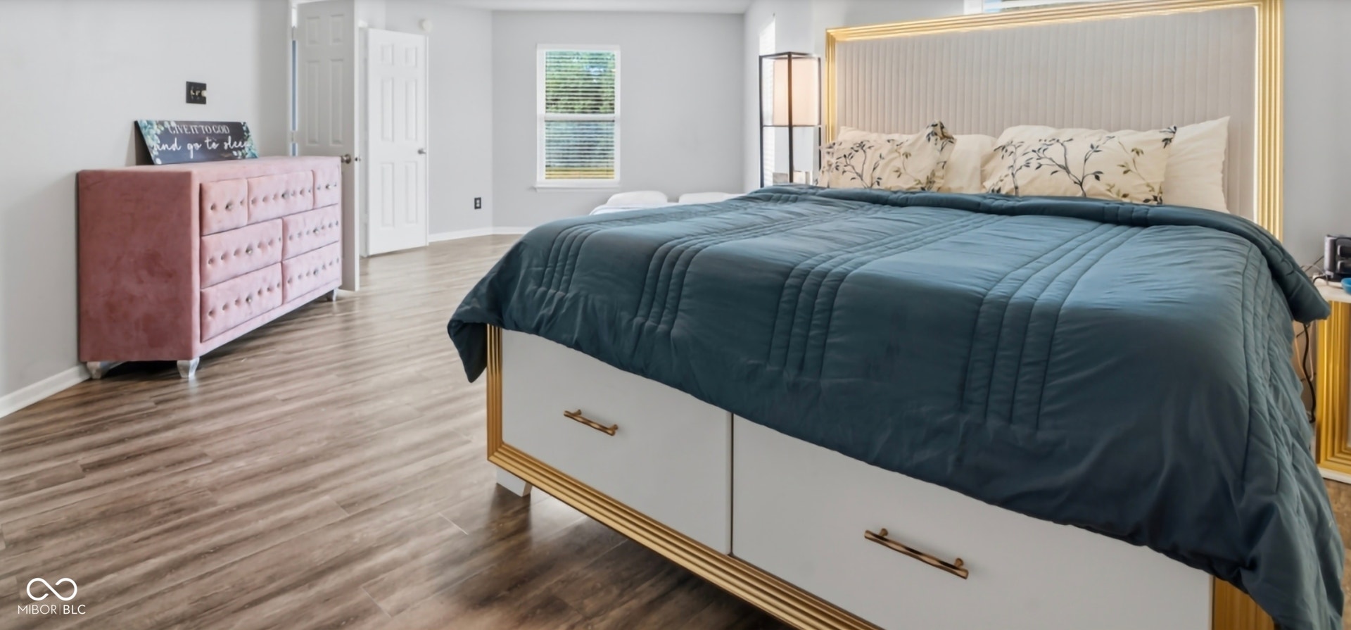 Spacious room featuring wood-finish flooring, light grey walls, and a large window