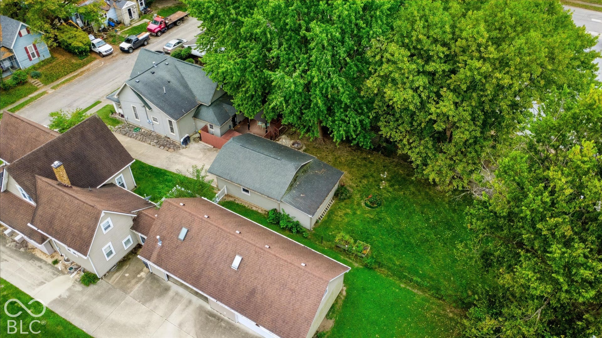 304 W 4th Street, Greenfield, IN 46140 Aerial perspective featuring a detached multi-car garage, concrete driveway, and expansive rear lawn with mature trees