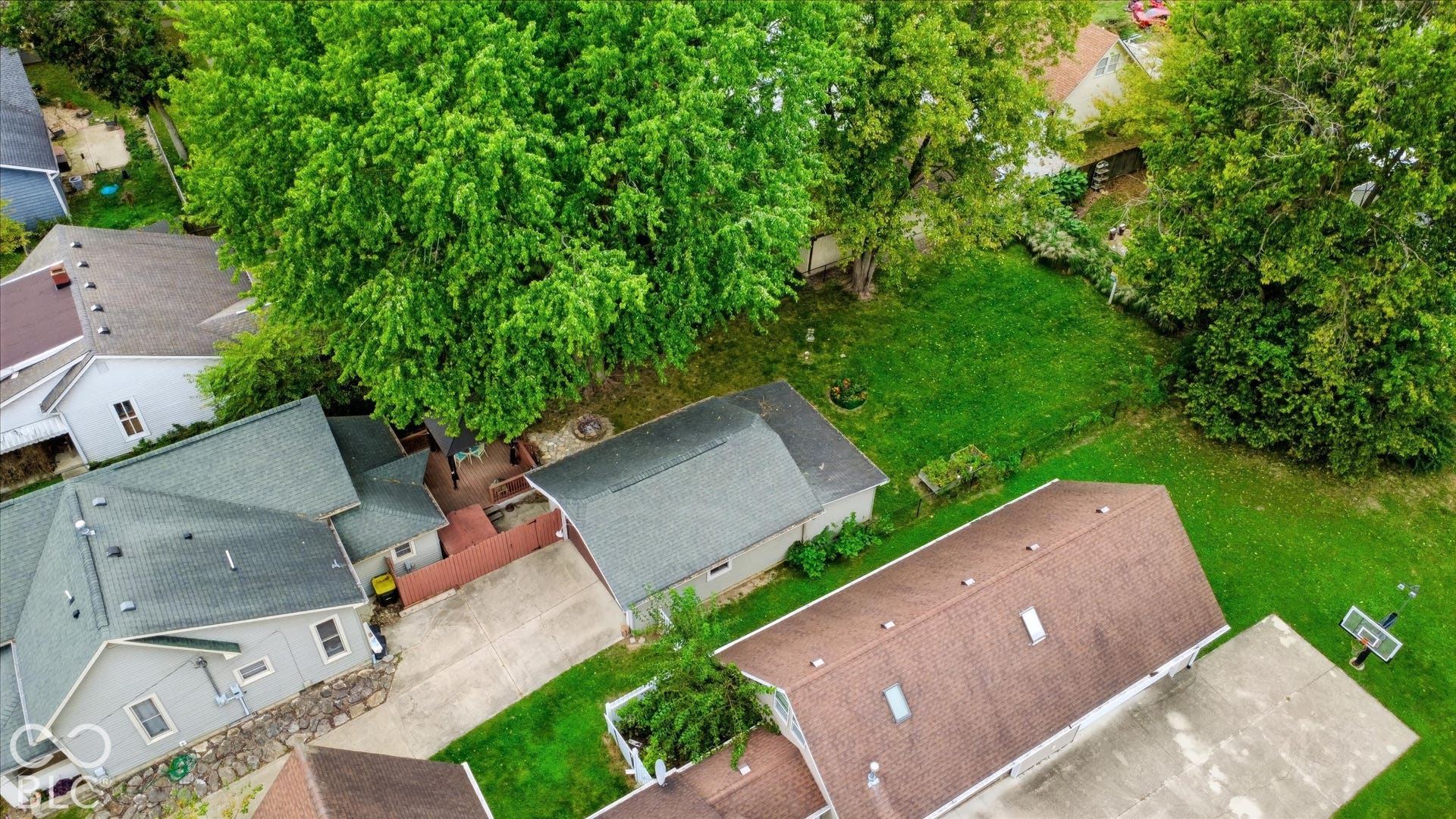 304 W 4th Street, Greenfield, IN 46140 Aerial perspective of a property featuring a concrete driveway, detached garage, hardscaped patio area, and mature trees on a level lot