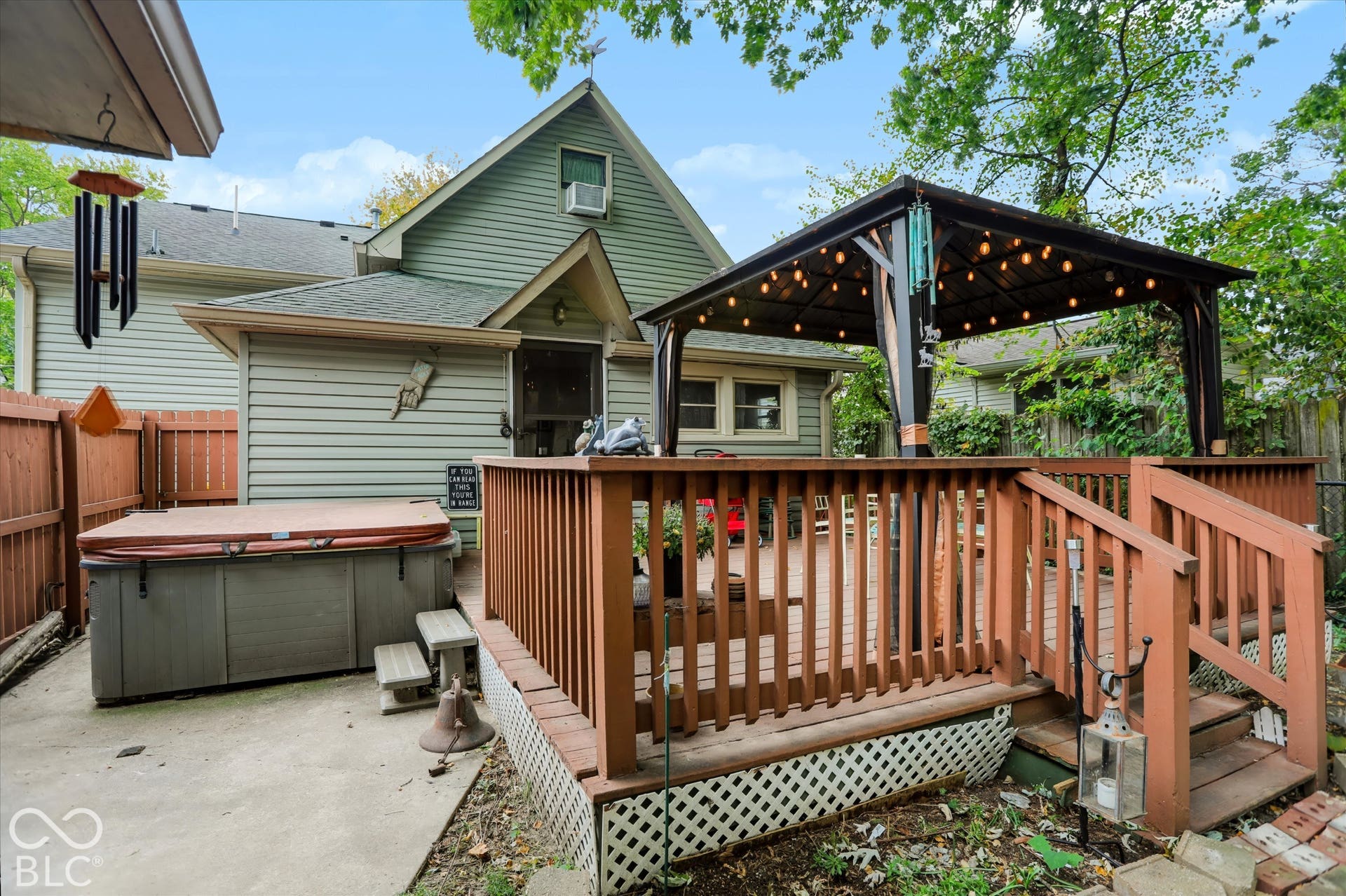 304 W 4th Street, Greenfield, IN 46140 Rear exterior featuring a raised wood deck with a built-in gazebo, wood privacy fencing, concrete hardscaping, and a hot tub