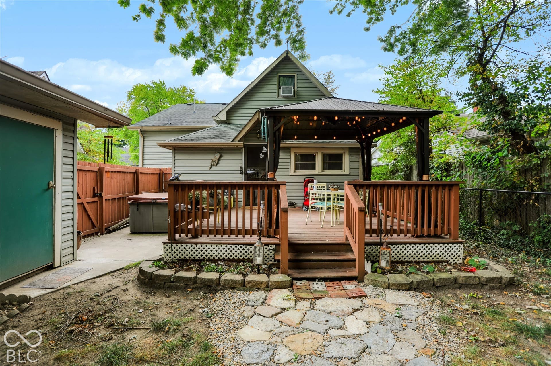 304 W 4th Street, Greenfield, IN 46140 Elevated wooden deck with integrated gazebo structure, concrete patio area, stone-style hardscaping, and wood privacy fencing