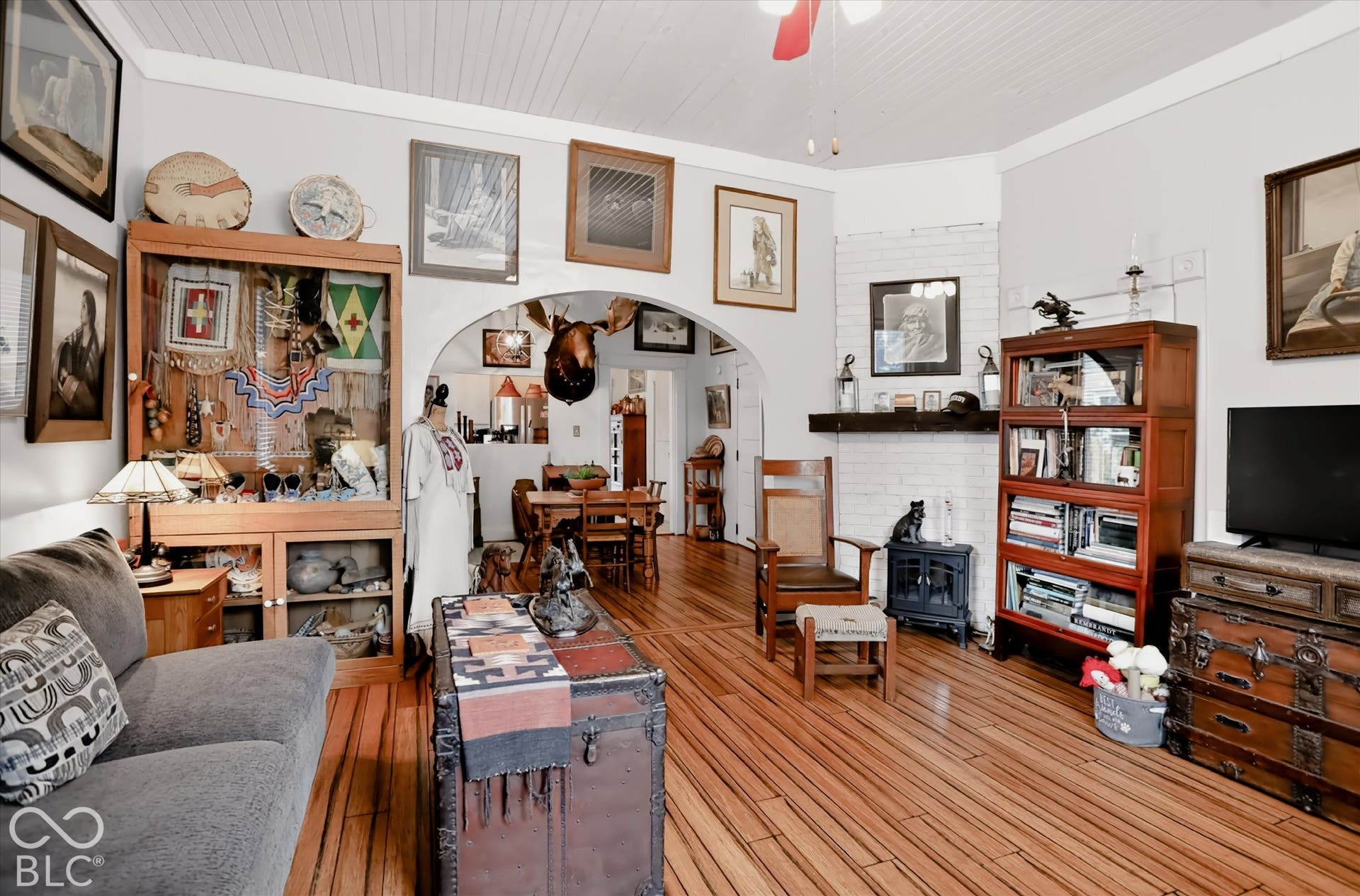 304 W 4th Street, Greenfield, IN 46140 Living area featuring wood-finish flooring, a painted brick fireplace surround, an arched entryway, and beadboard ceiling paneling