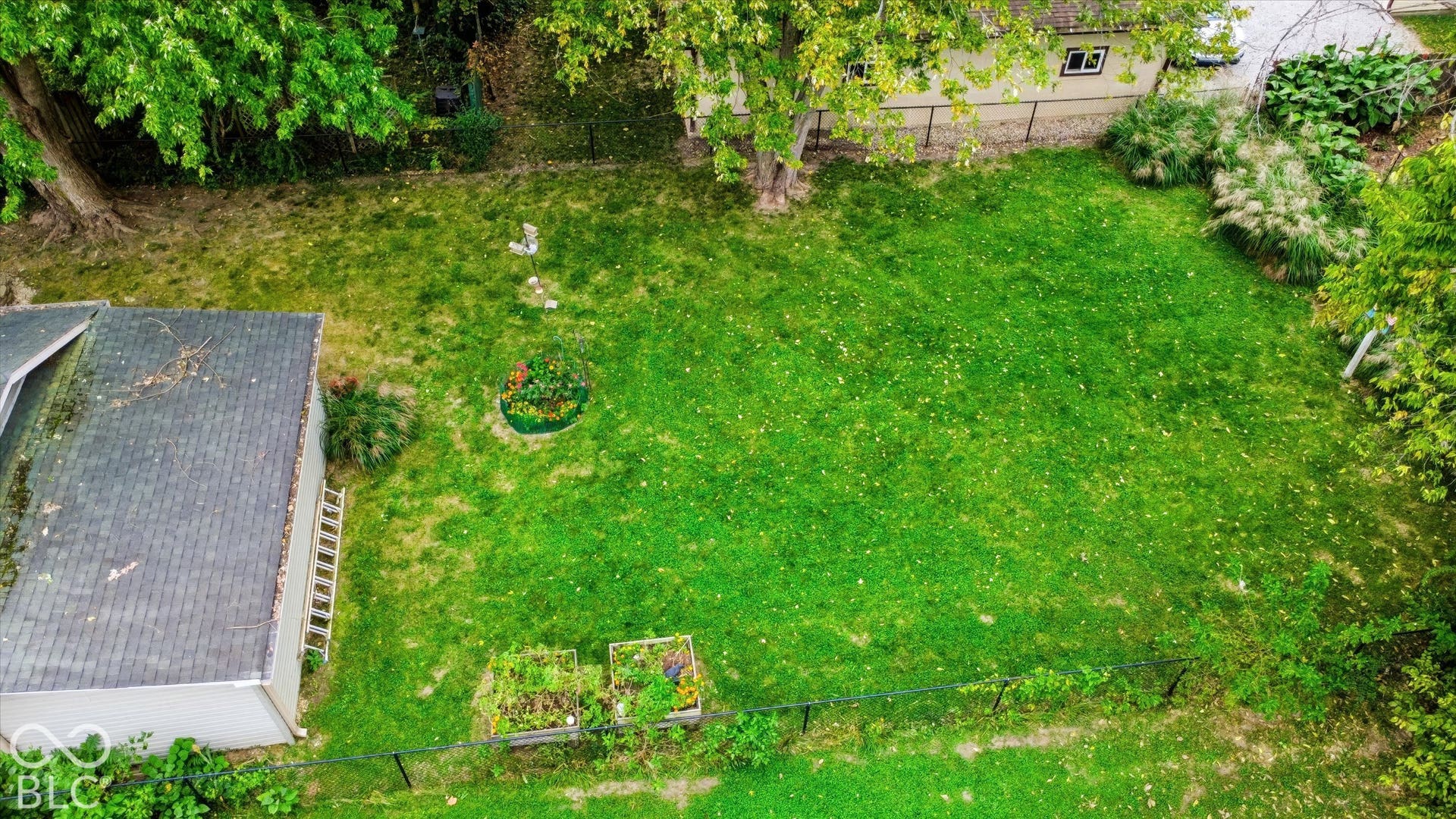 304 W 4th Street, Greenfield, IN 46140 Fenced backyard featuring a manicured lawn, established shade trees, perimeter fencing, and raised planting beds