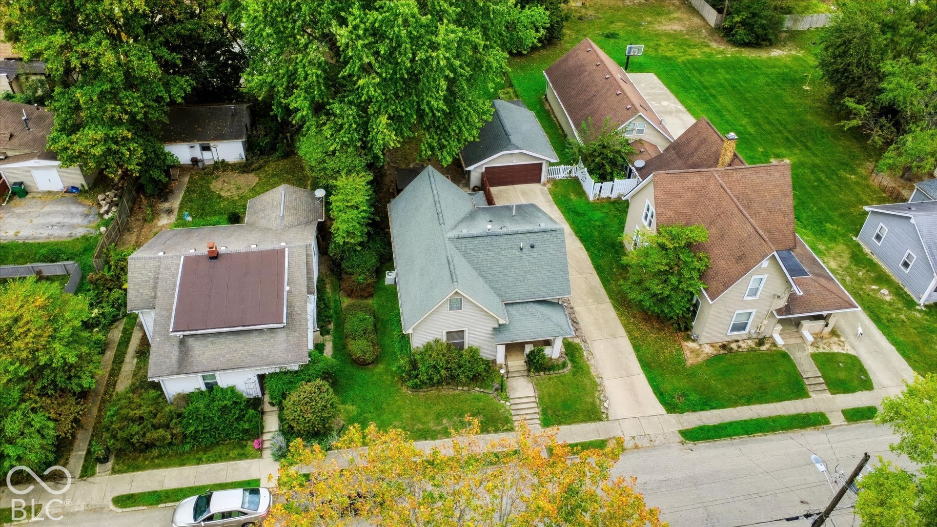 304 W 4th Street, Greenfield, IN 46140 Aerial perspective featuring a shingled roof, concrete driveway, detached garage, and mature tree canopy