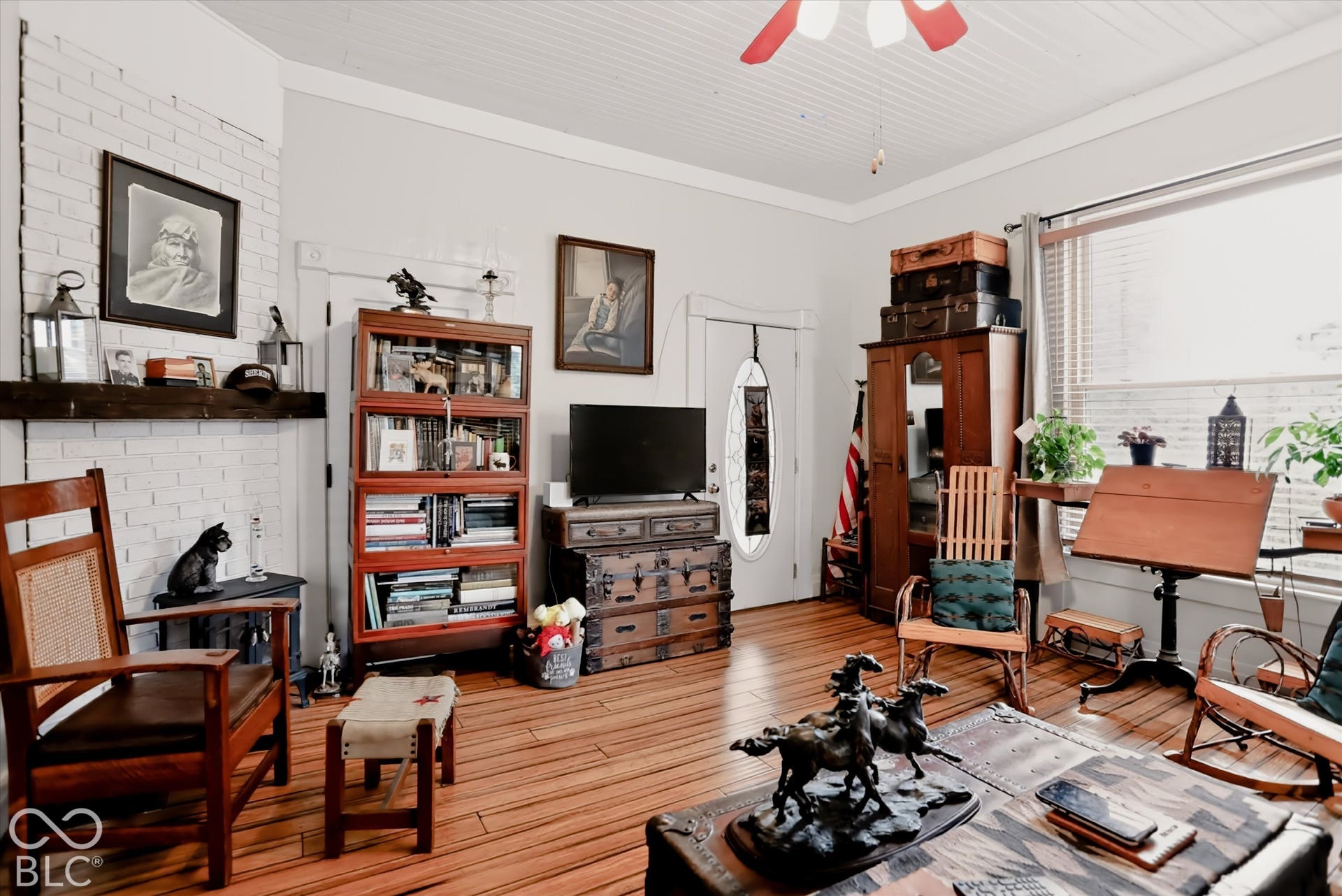 304 W 4th Street, Greenfield, IN 46140 Painted brick fireplace with a dark timber mantel, beadboard ceiling, wood-finish flooring, and a glass-paneled entry door