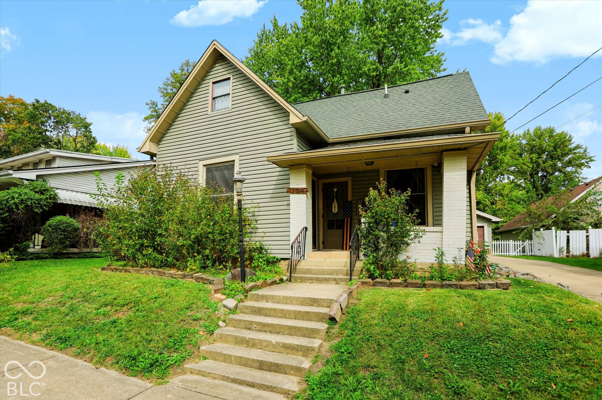304 W 4th Street, Greenfield, IN 46140 Exterior featuring horizontal siding, a covered front porch with masonry column supports, concrete steps, and a gabled roofline