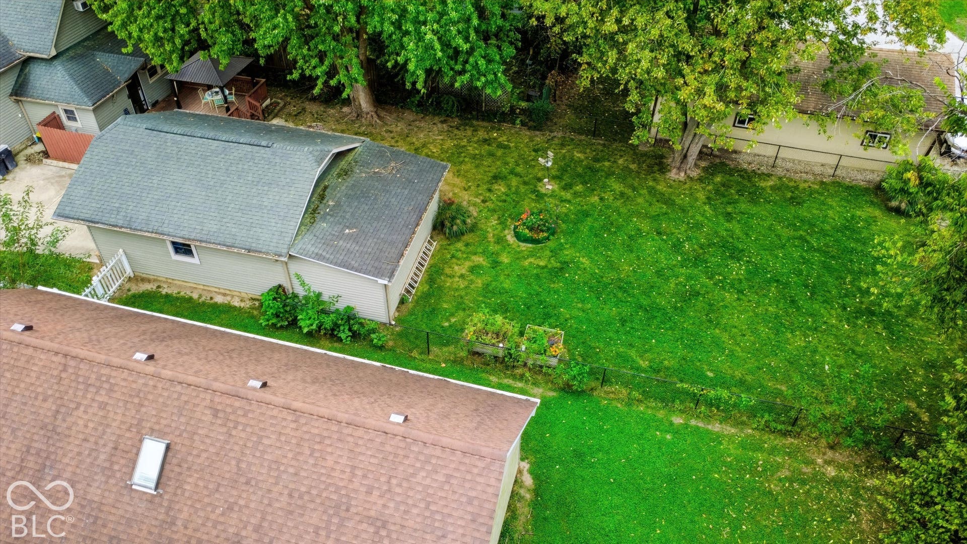 304 W 4th Street, Greenfield, IN 46140 Expansive backyard featuring a grass lawn, mature trees, a detached garage with asphalt shingle roofing, and a wooden gazebo