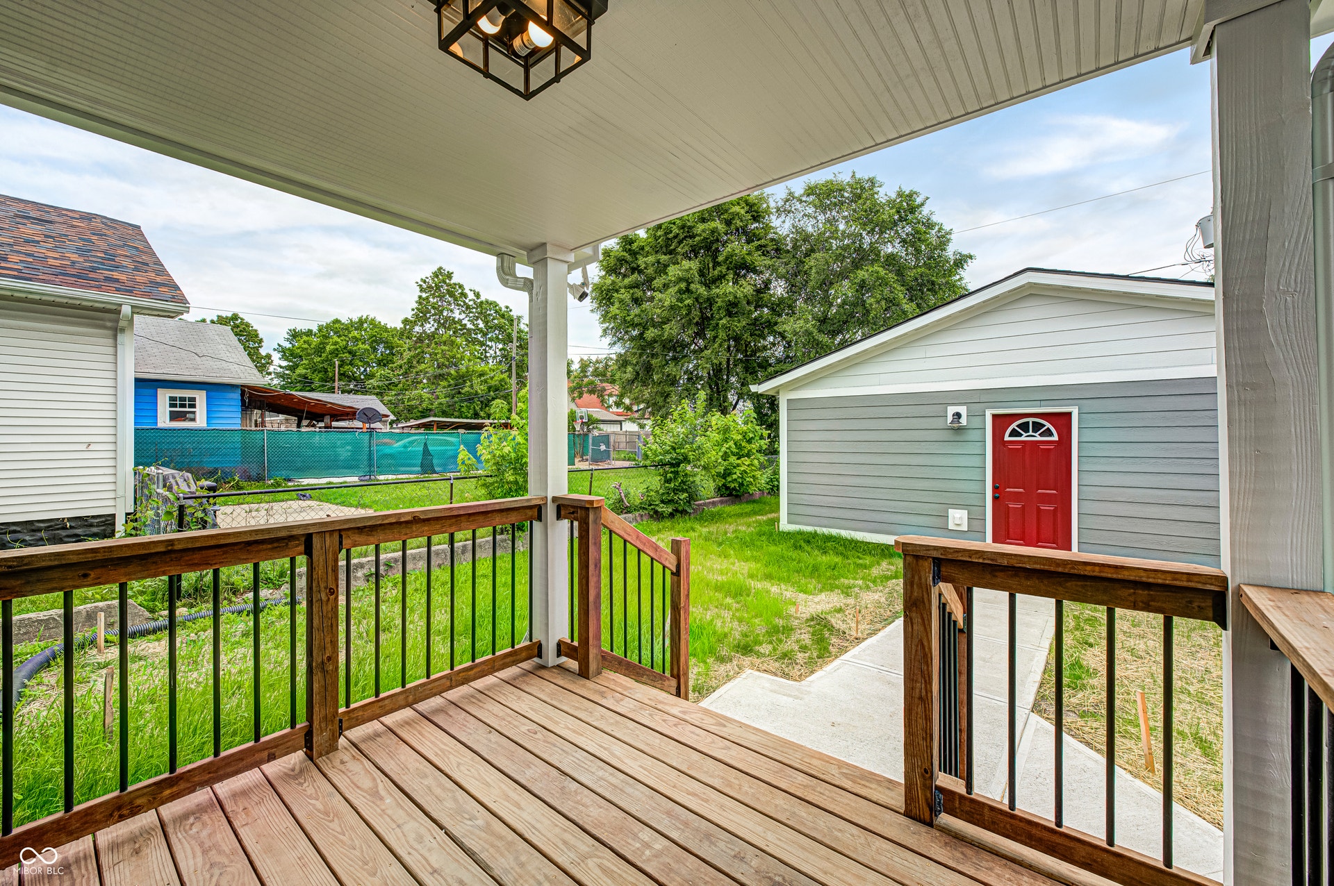 Covered wood-finish deck with dark balusters, offering exterior access