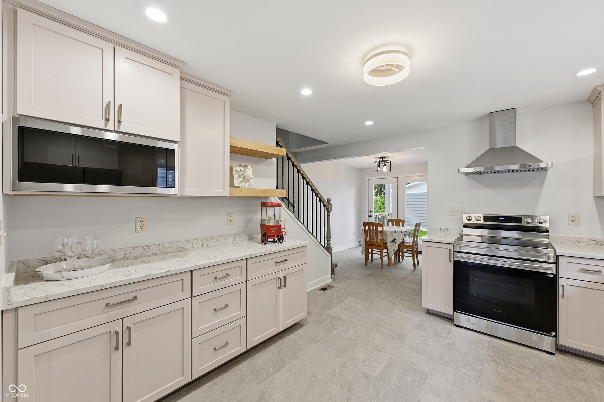 Contemporary kitchen featuring light-toned cabinetry, stainless steel appliances, stone-finish countertops, and wood-finish open shelving