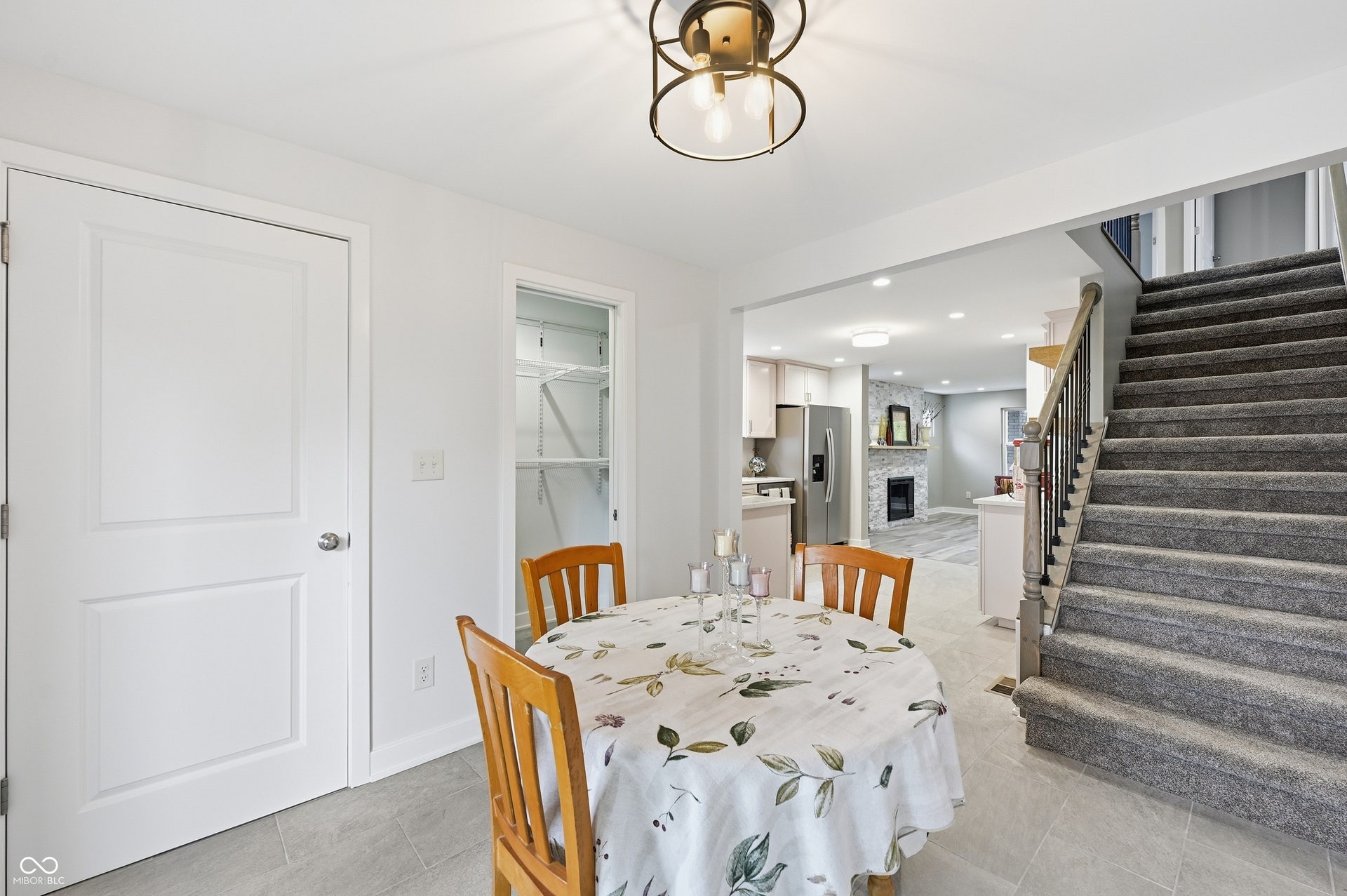 Open concept floor plan featuring a carpeted staircase with wood railing, recessed lighting, and tile flooring