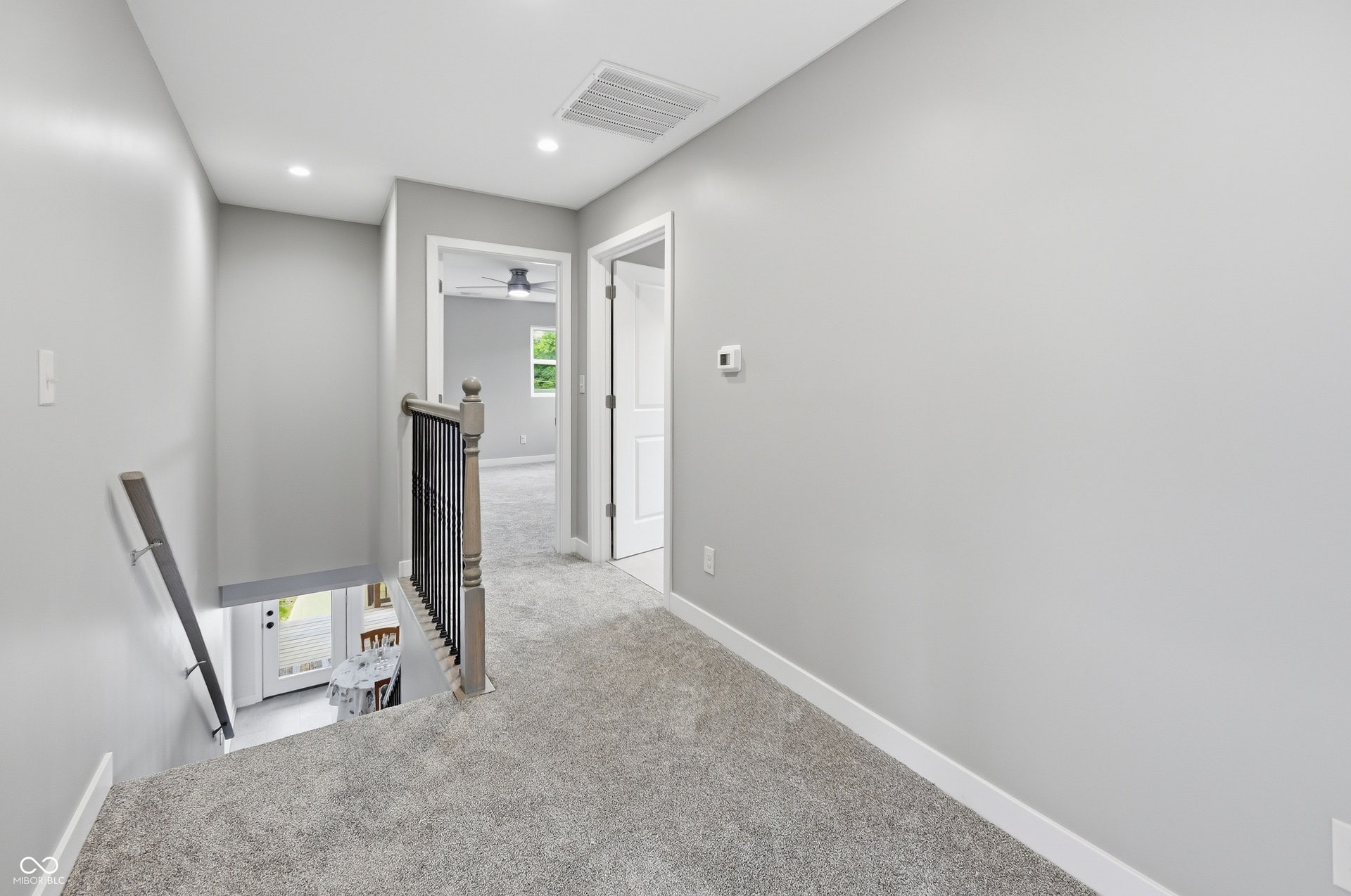 Carpeted upper hallway featuring light gray wall paint, white baseboards, and recessed lighting