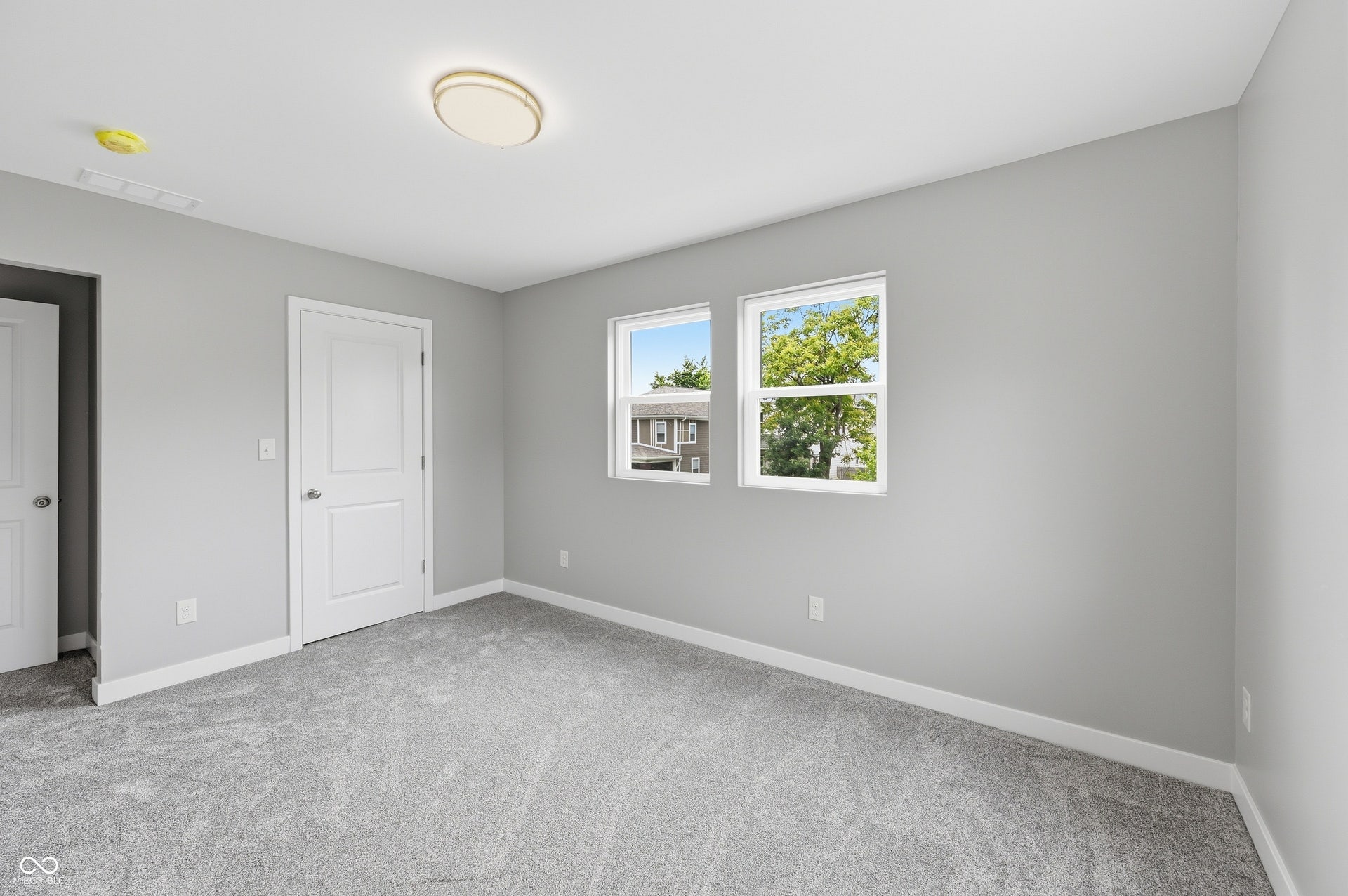 Light gray wall paint with white trim, gray carpet flooring, and a contemporary ceiling light fixture