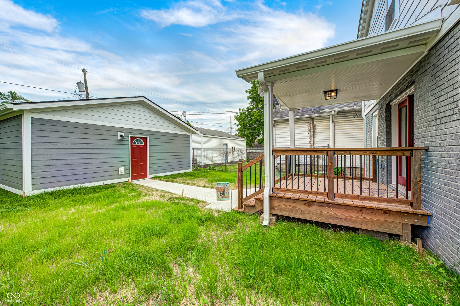 Rear covered porch featuring wood decking and black metal balusters