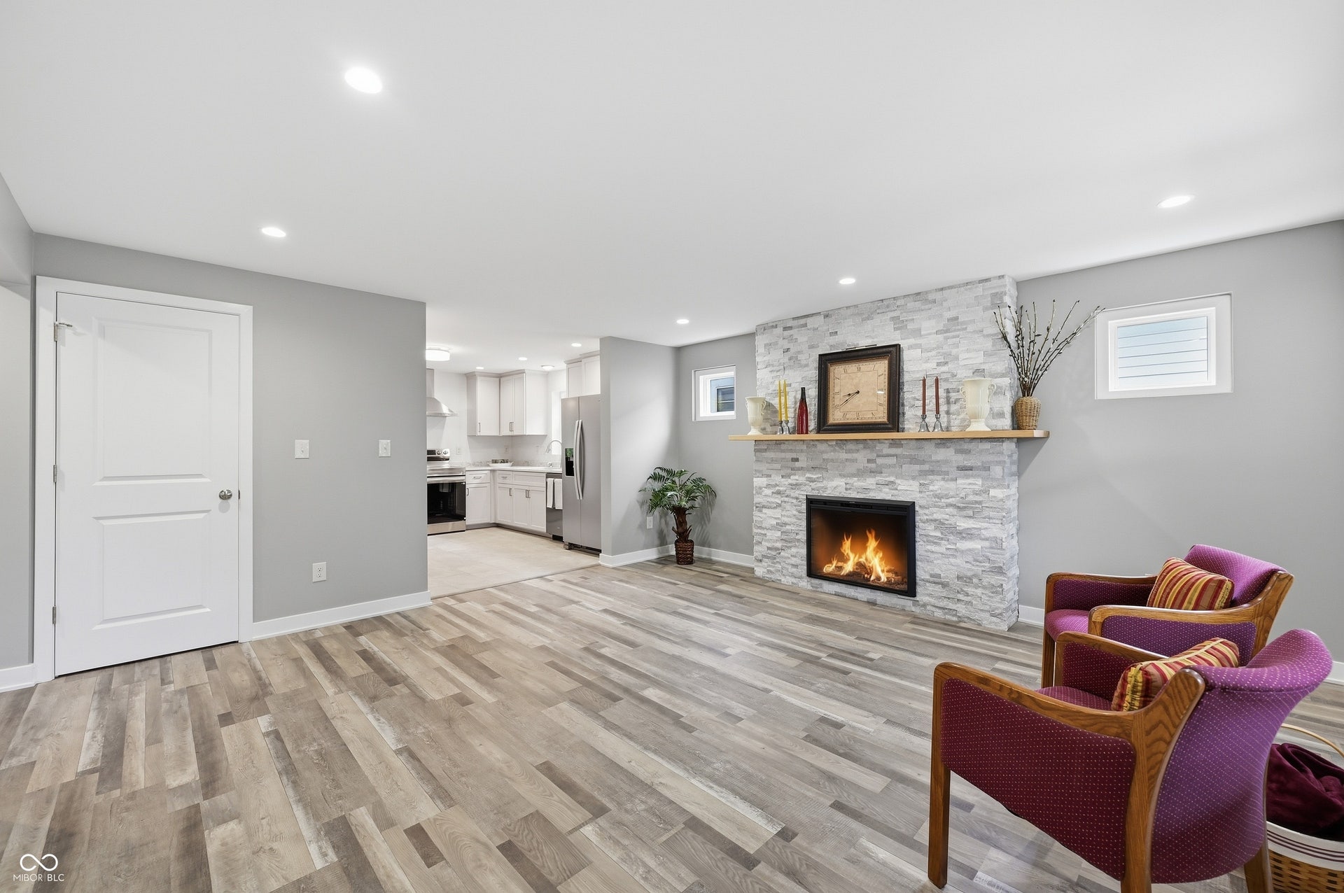 Living area featuring wood-finish flooring, recessed lighting, and a stone-clad fireplace with a light wood mantel