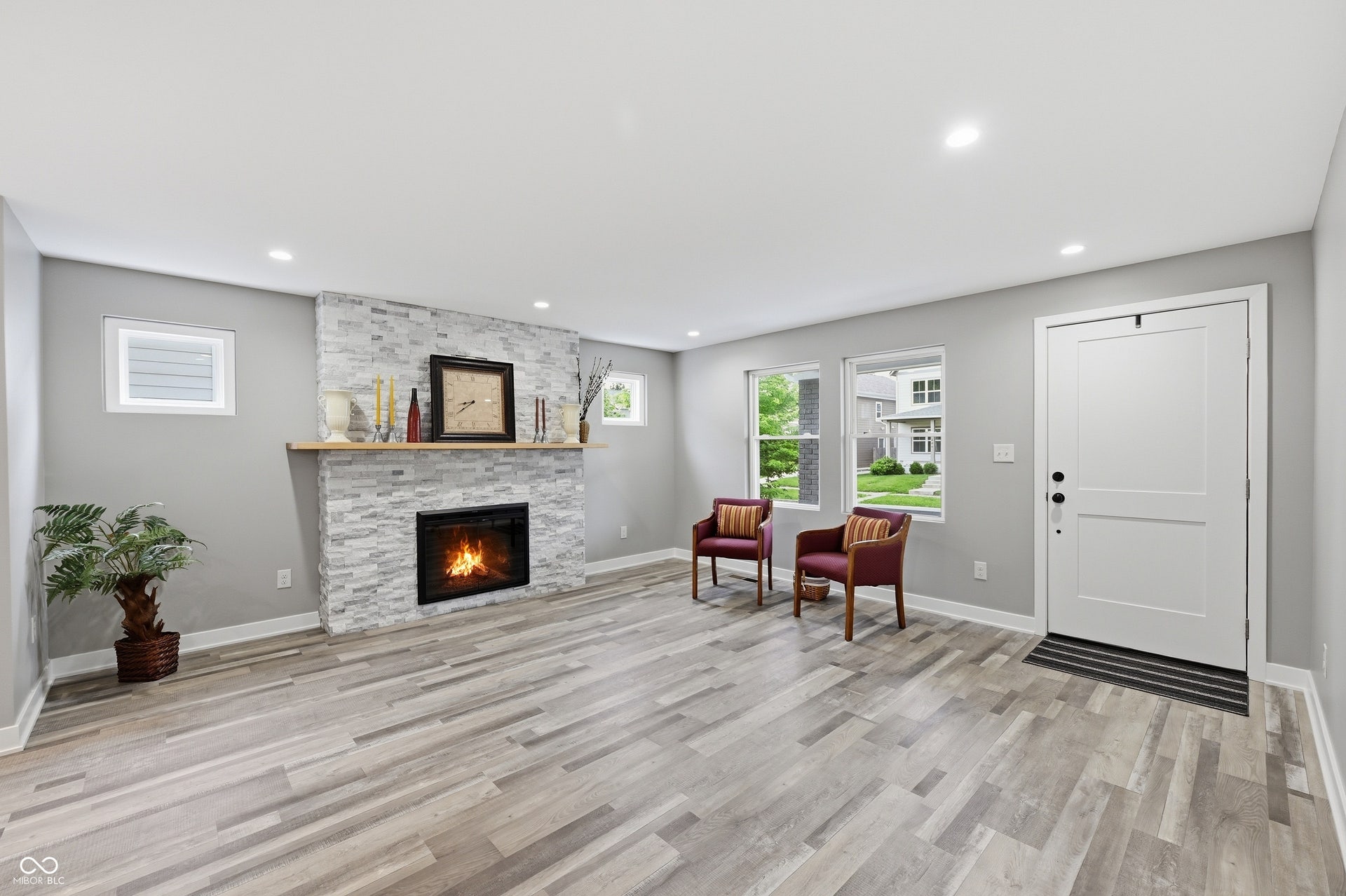 Spacious room featuring a stone-clad fireplace with a wood mantel, recessed lighting, and wood-finish flooring