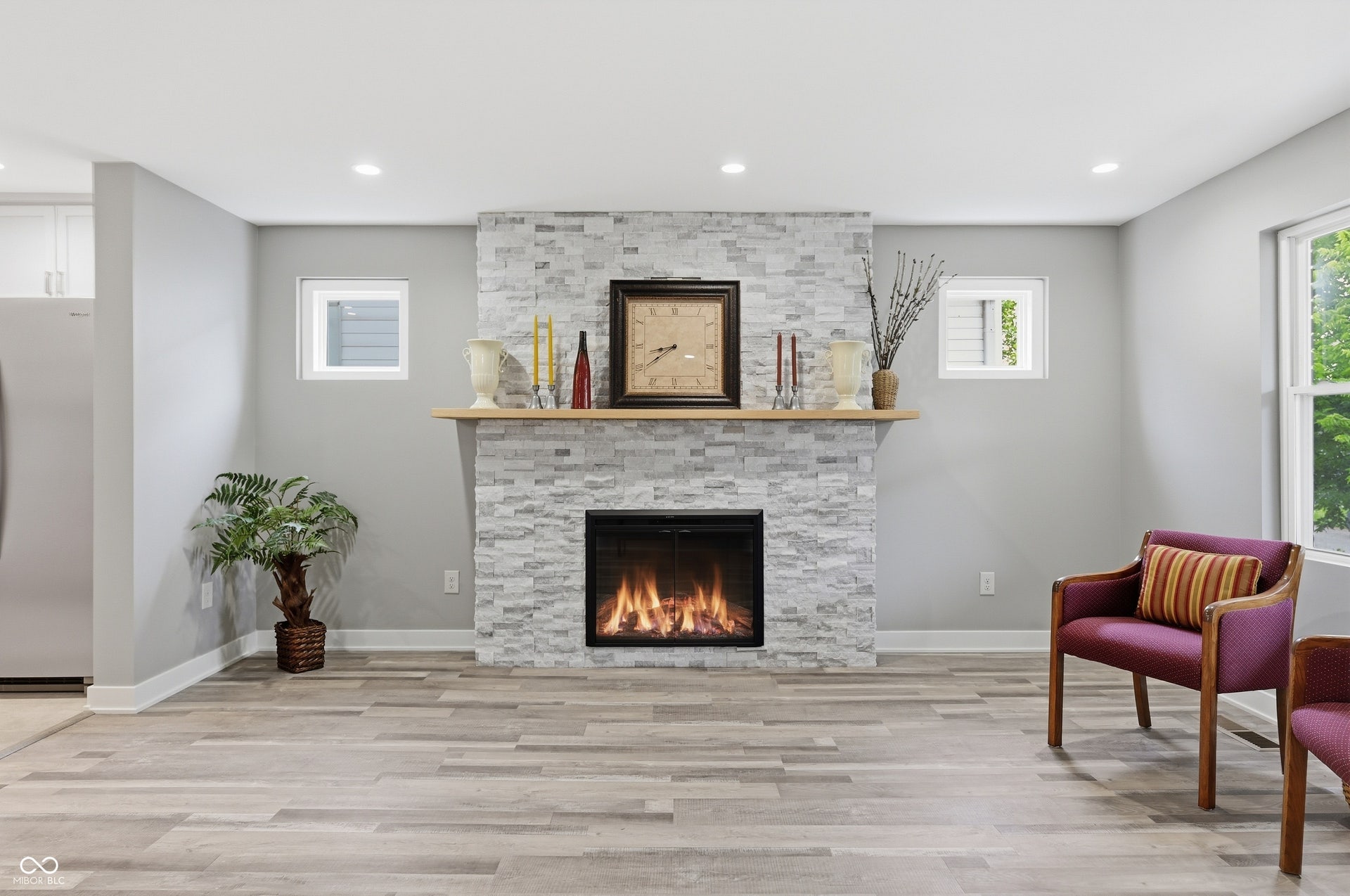 Stone-clad fireplace with an integrated electric insert and a light wood mantel