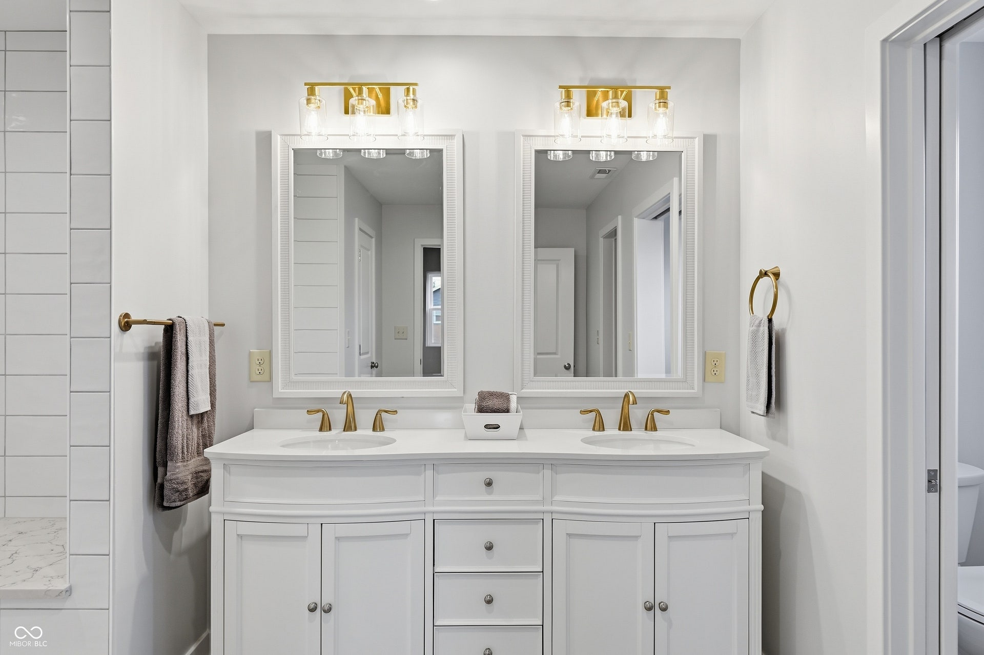 Dual vanity with white cabinetry, gold-finish fixtures, and integrated sinks