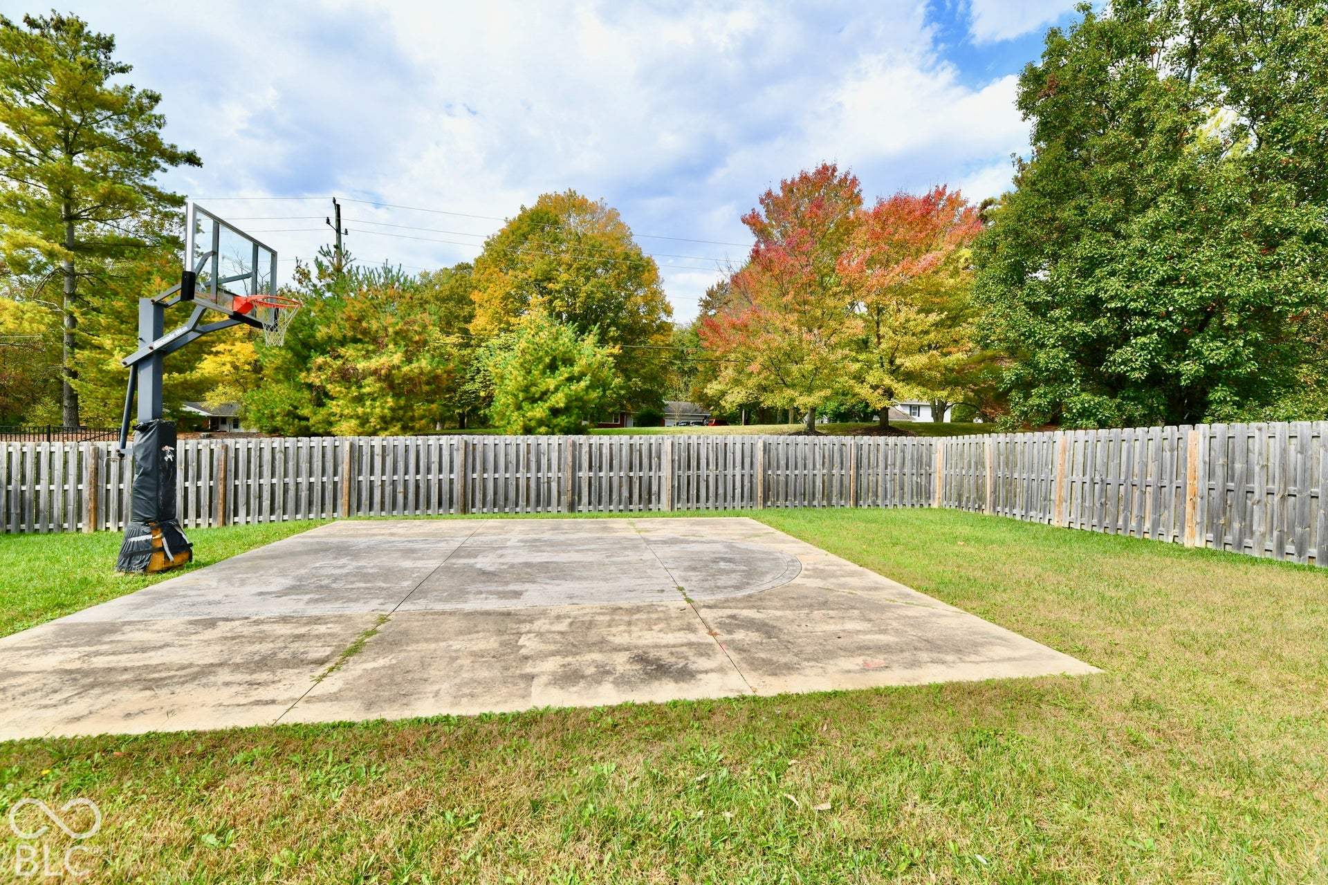 Backyard featuring a concrete sports court, a basketball goal, and a perimeter privacy fence