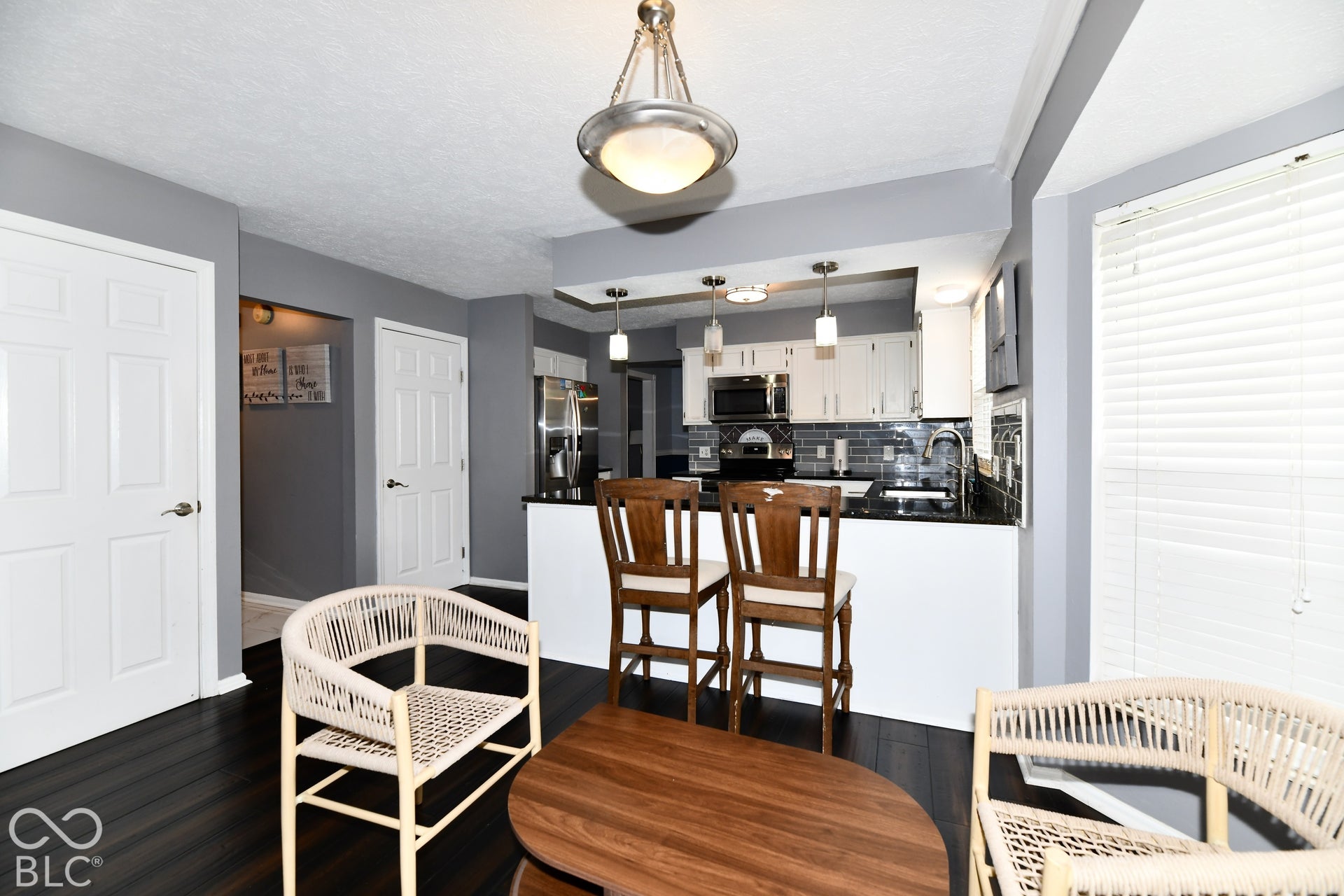 Kitchen featuring white cabinetry, dark countertops, a subway tile backsplash, stainless steel appliances, and wood-finish flooring
